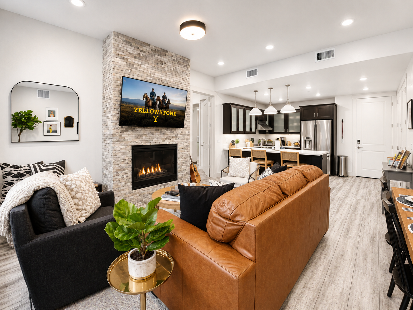Sink into plush leather seating in your open-concept living space, where a stone fireplace and large TV set the scene for cozy evenings. The modern kitchen awaits your culinary adventures.