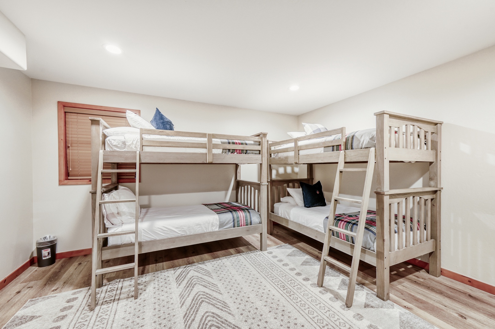 Two sturdy wooden bunk beds create a fun sleeping space where kids can make memories together in this bright, cheerful room.