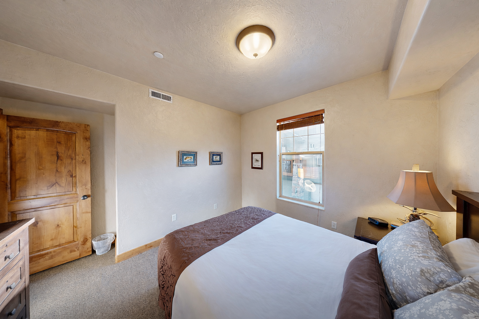 Relax in this cozy bedroom featuring a comfortable queen-size bed, nightstands with lamps, and ample closet/dresser storage space. A quiet retreat for rest and relaxation!