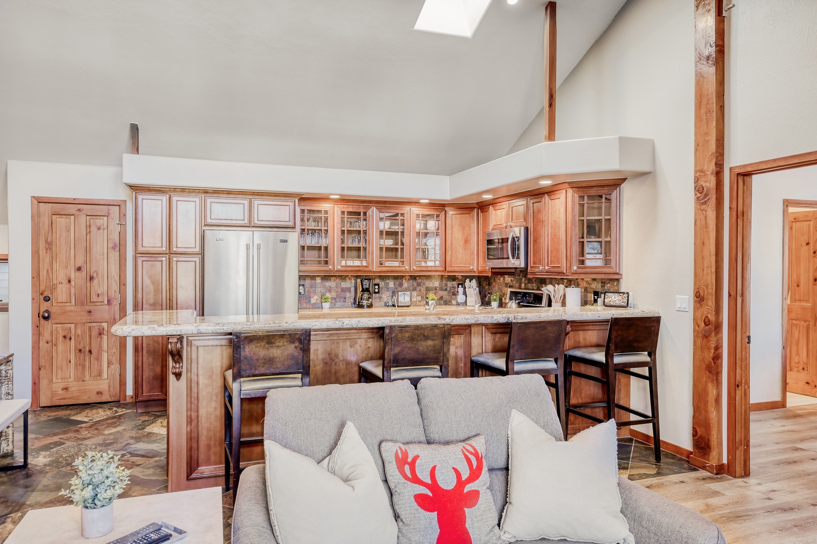 Your open-concept living flows seamlessly into the fully equipped kitchen, where warm wood cabinetry and granite counters invite you to gather around the breakfast bar.