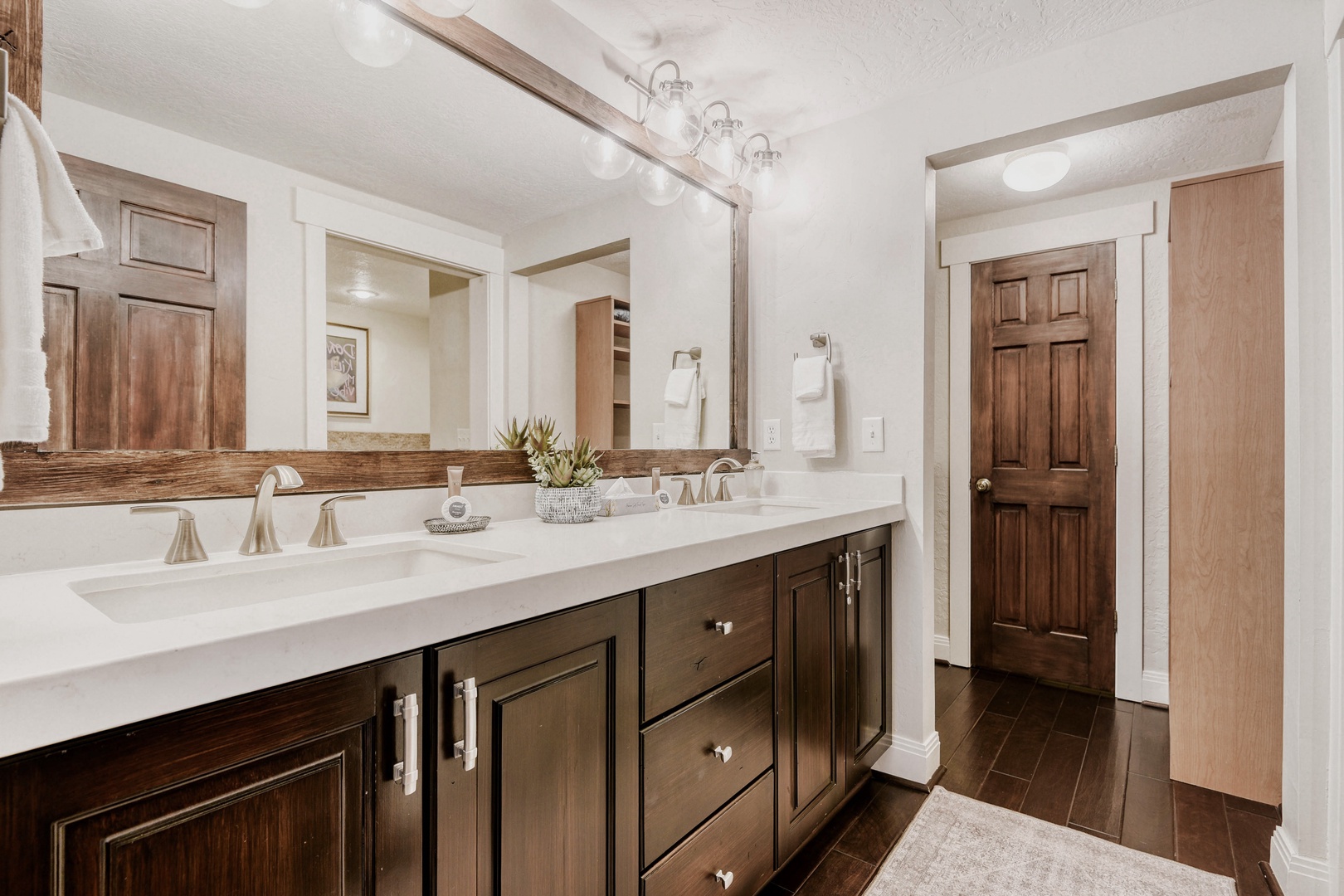 Refresh in your spacious master bathroom featuring dual vanities, elegant wood accents, and premium fixtures designed for comfort.
