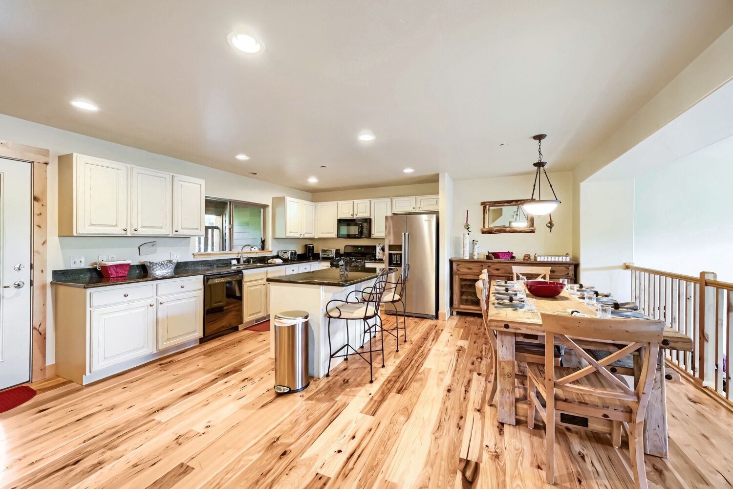 Gather around this spacious dining table after exploring, with a fully-equipped kitchen ready for your culinary adventures. Warm wood floors and natural light create the perfect backdrop for memorable meals.