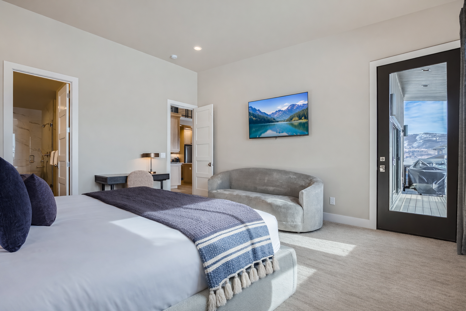 Unwind in your elegant bedroom featuring crisp linens, a cozy reading nook, and stunning mountain views through floor-to-ceiling windows.