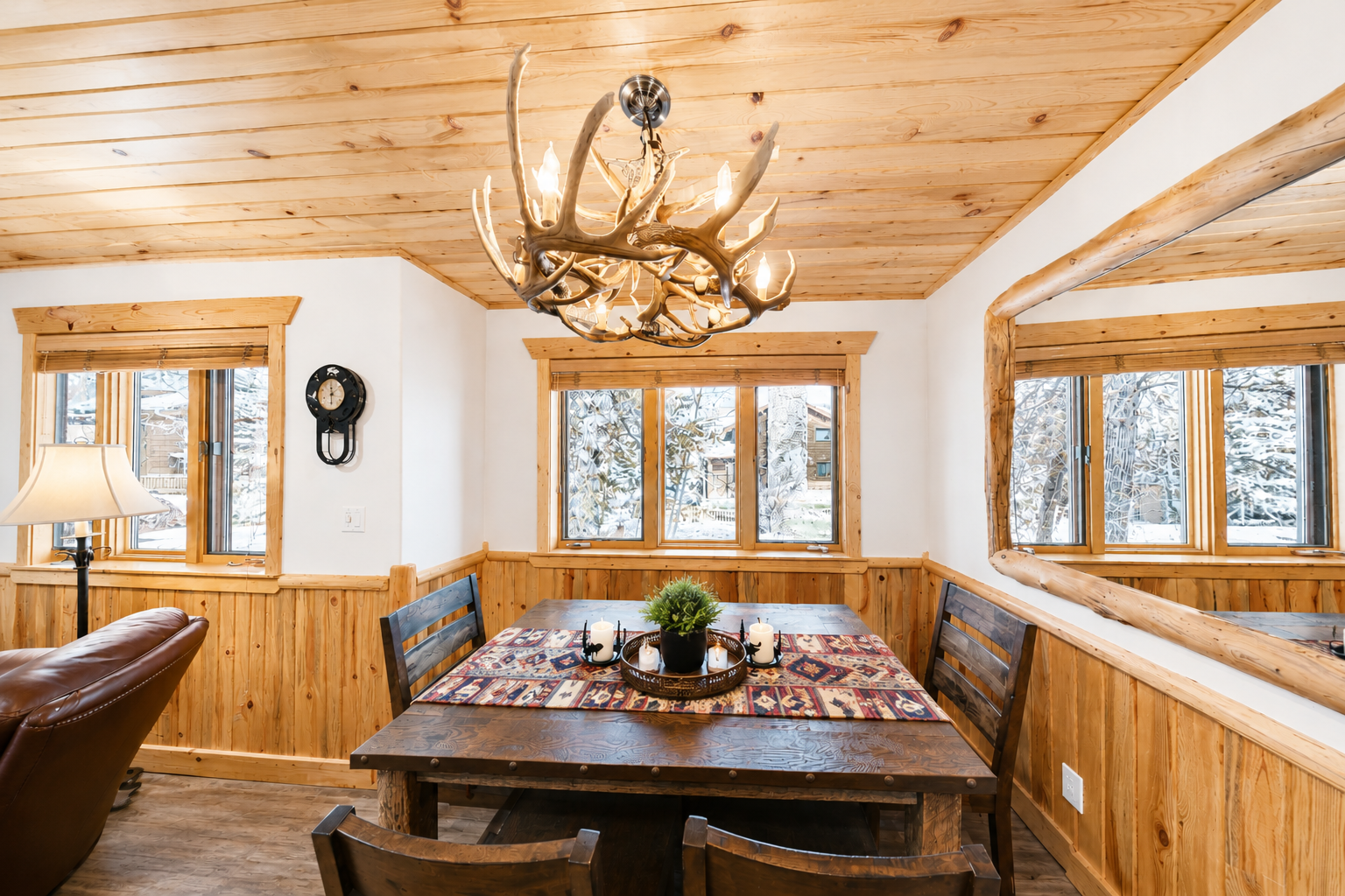 Gather around the rustic dining table under the antler chandelier and enjoy warm meals with loved ones while snow-dusted pines frame your cozy mountain retreat.