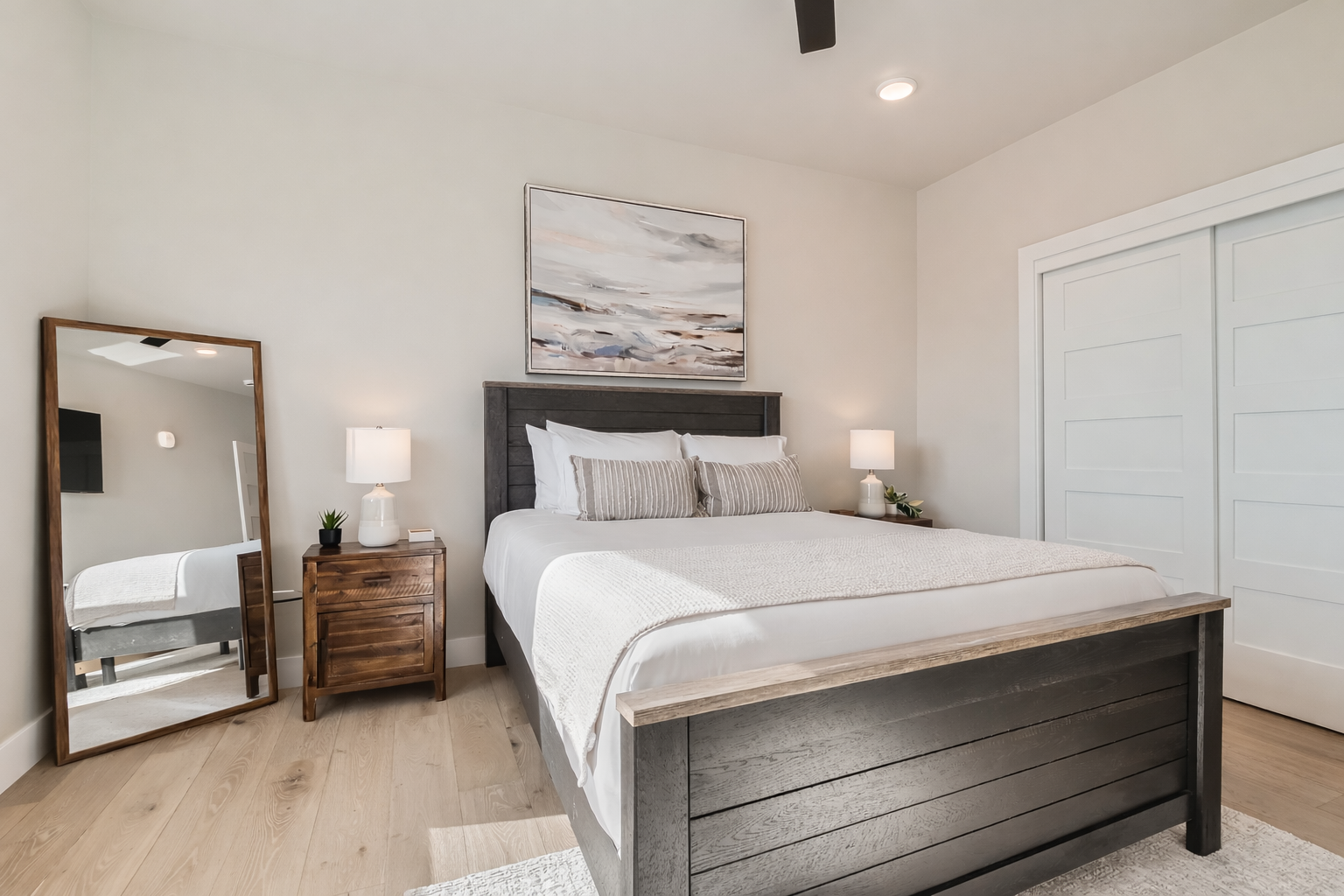 Sink into crisp white linens and wake refreshed in your serene bedroom with modern coastal vibes and warm wood accents.
