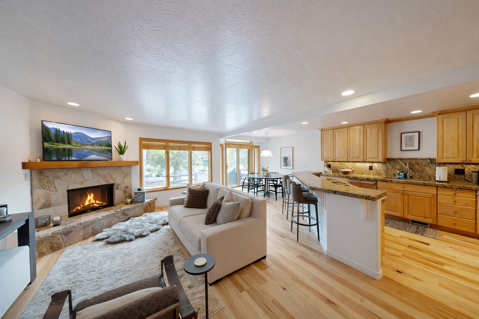 This spacious living room features a cozy fireplace and large windows offering scenic mountain views. Relax on the comfortable sectional while enjoying the tranquil atmosphere.