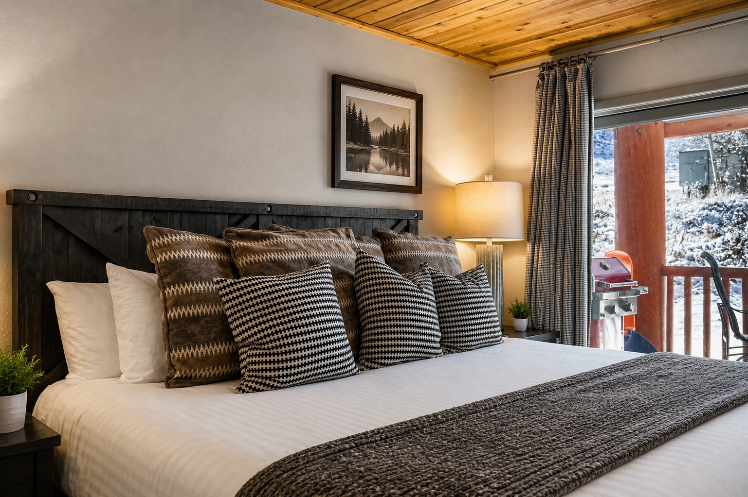 Sink into crisp white linens and layered textures in your cozy mountain bedroom. The rustic wood ceiling and warm lighting create a peaceful retreat after a day of adventure.