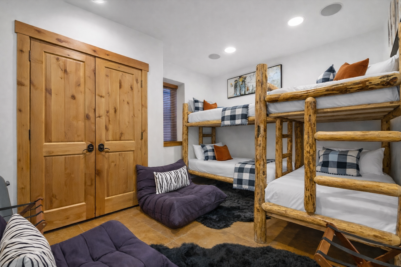 Gather with family in your cozy bunk room featuring rustic log frames and soft plaid bedding for memorable nights together.