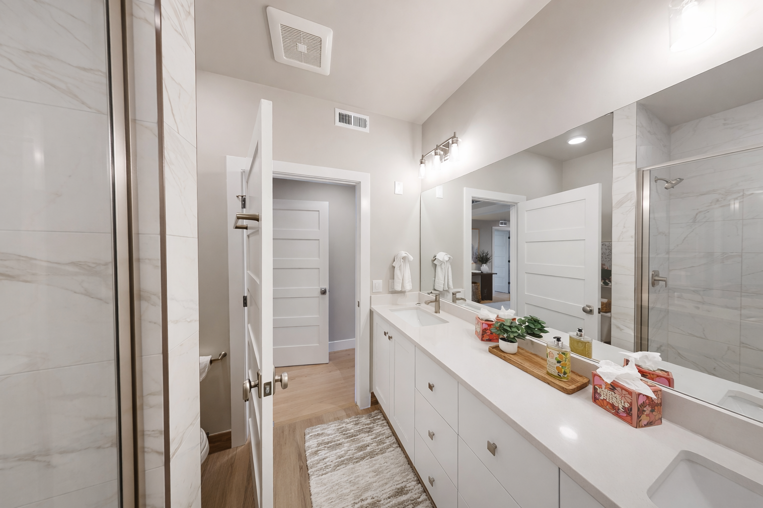 Unwind in this serene, spa-like bathroom featuring a sleek double vanity, crisp white cabinetry, and a spacious glass-enclosed shower. The perfect spot to refresh and recharge in luxury.