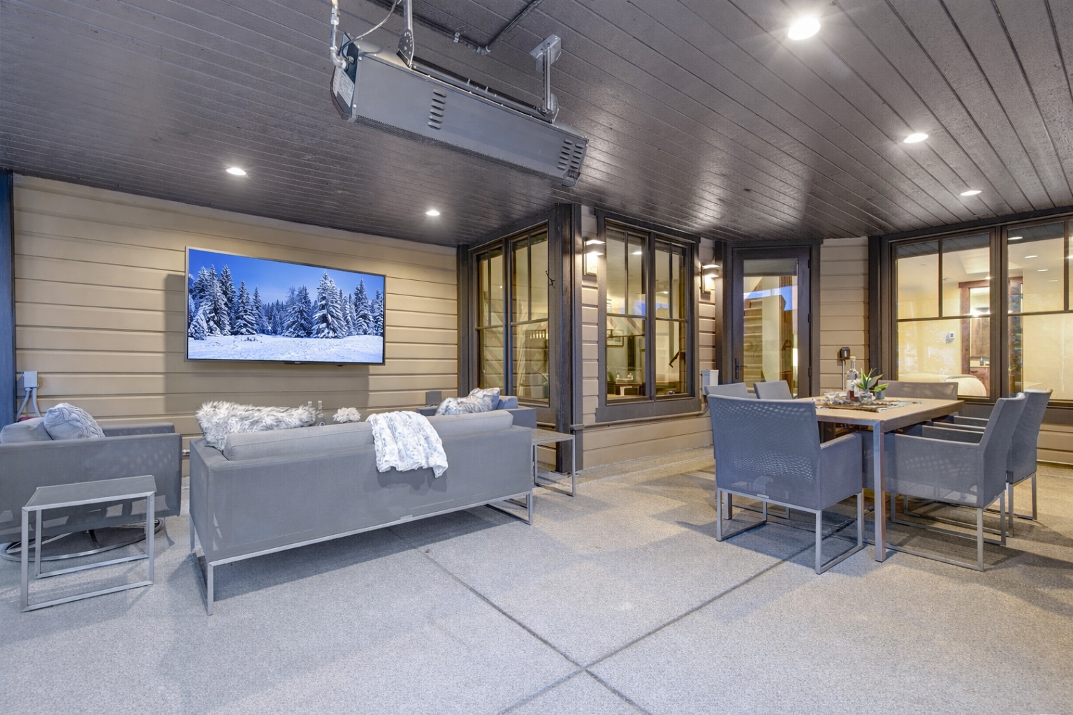 Unwind on your private terrace with modern seating, TV, and views of cozy interiors through floor-to-ceiling windows.