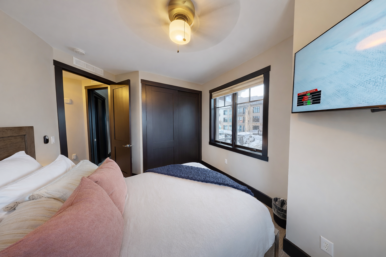 Drift off in your cozy bedroom with plush bedding, city views, and modern amenities including a wall-mounted TV for your relaxation.