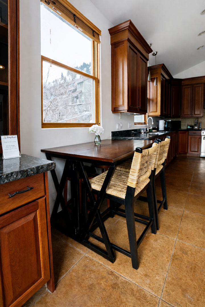 Gather around the breakfast bar where rich wood cabinets meet modern convenience—your morning coffee tastes even better with snowy mountain views. Unit A