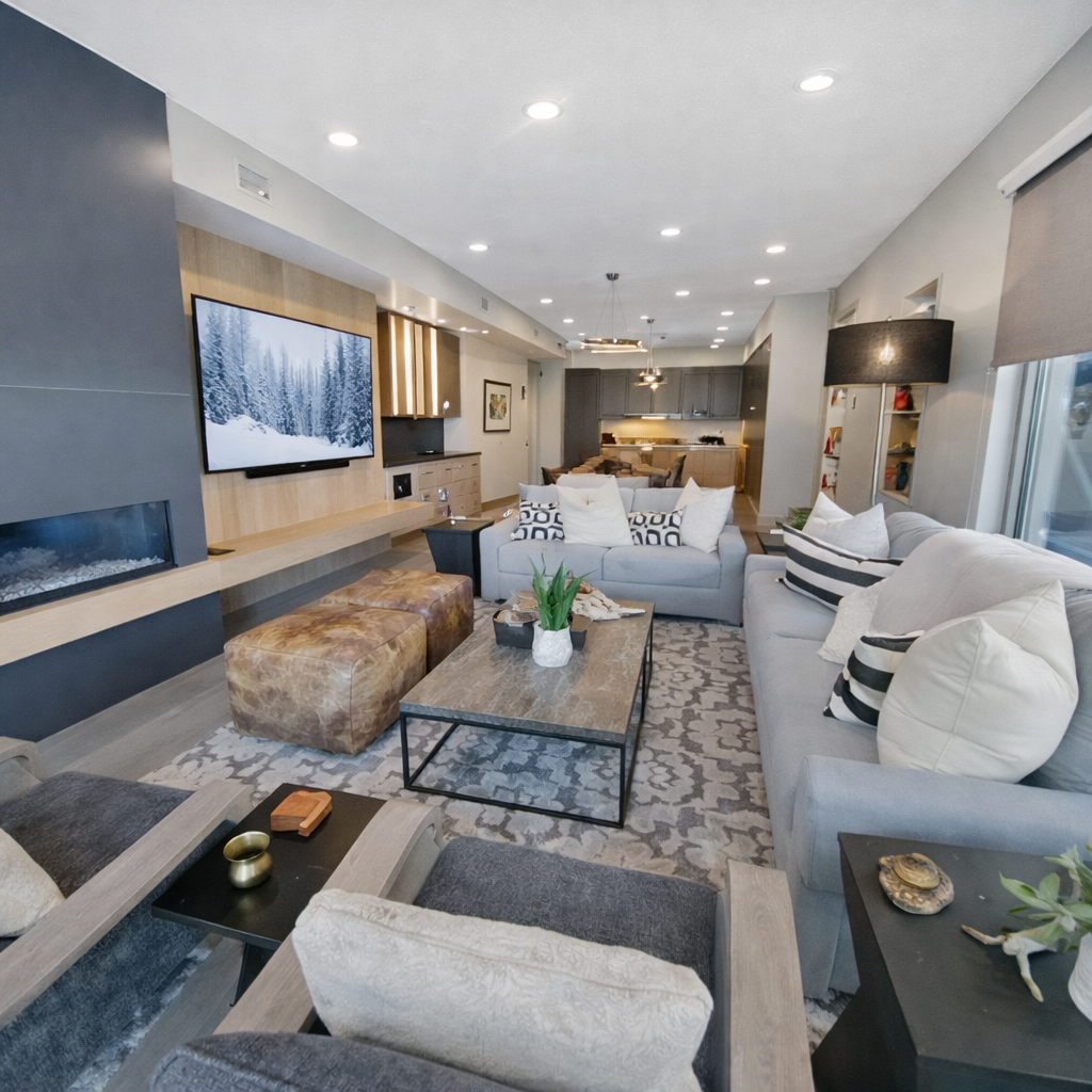 Relax in this chic open-concept living area featuring a cozy fireplace, large TV, and comfortable seating. Perfect for entertaining or unwinding after a day of adventure.