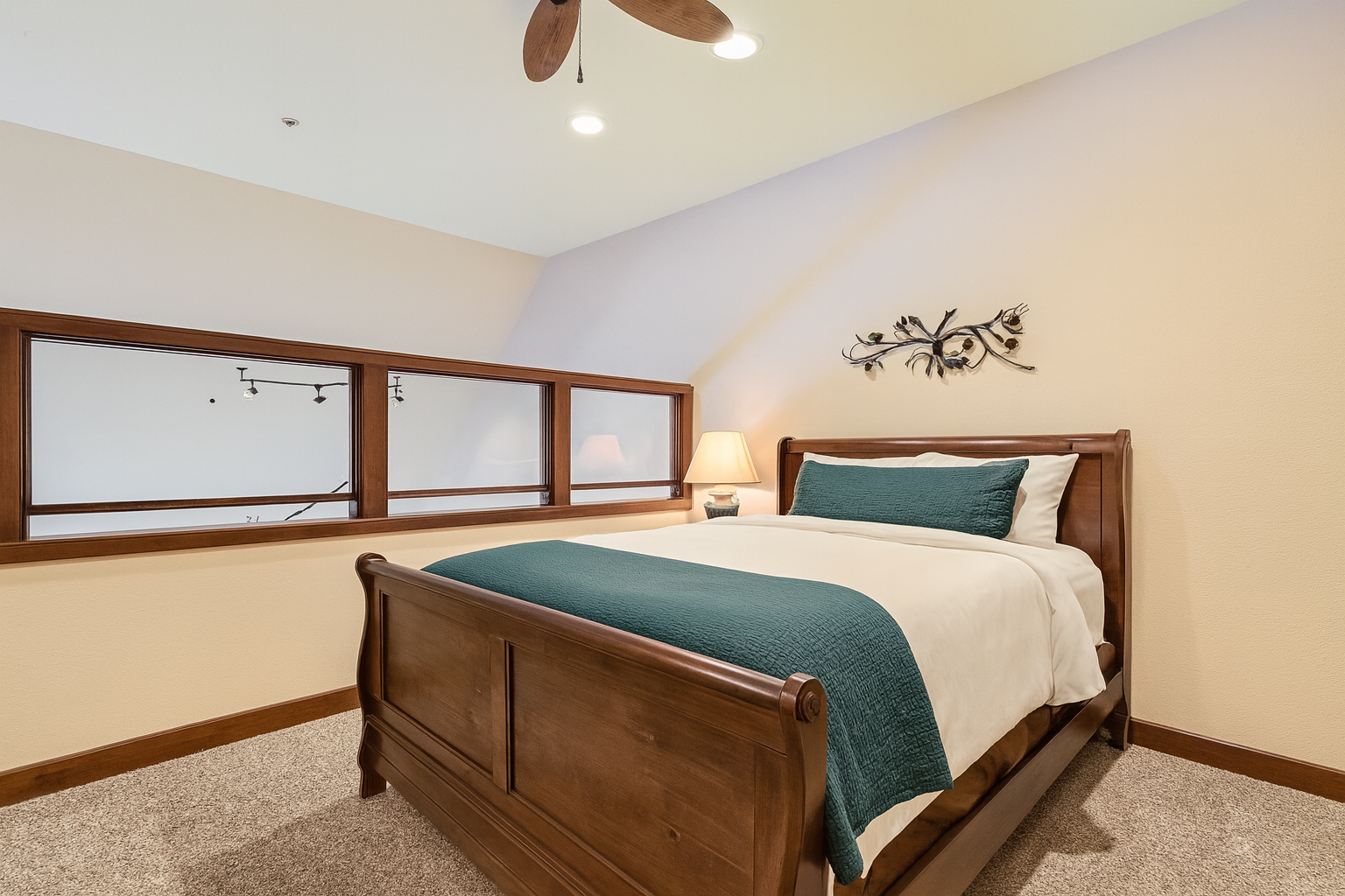 Relax in your comfortable bedroom featuring a beautiful wooden sleigh bed with crisp linens and elegant teal accents, complete with bedside lighting for your evening reading.