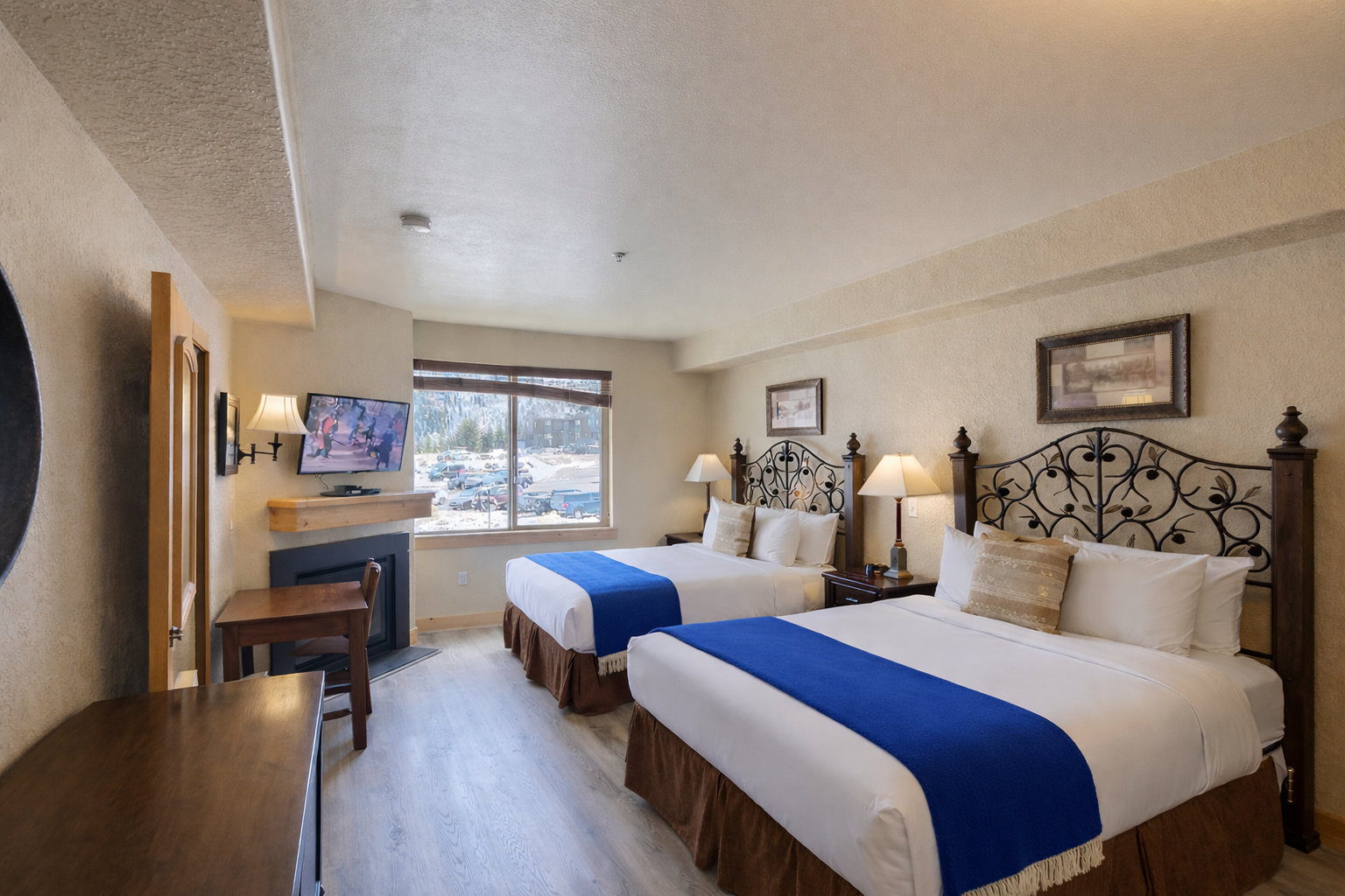This spacious guest room features two plush queen beds with ornate wrought-iron headboards. Enjoy the convenience of a private kitchenette and sleek wood flooring, perfect for a group getaway.