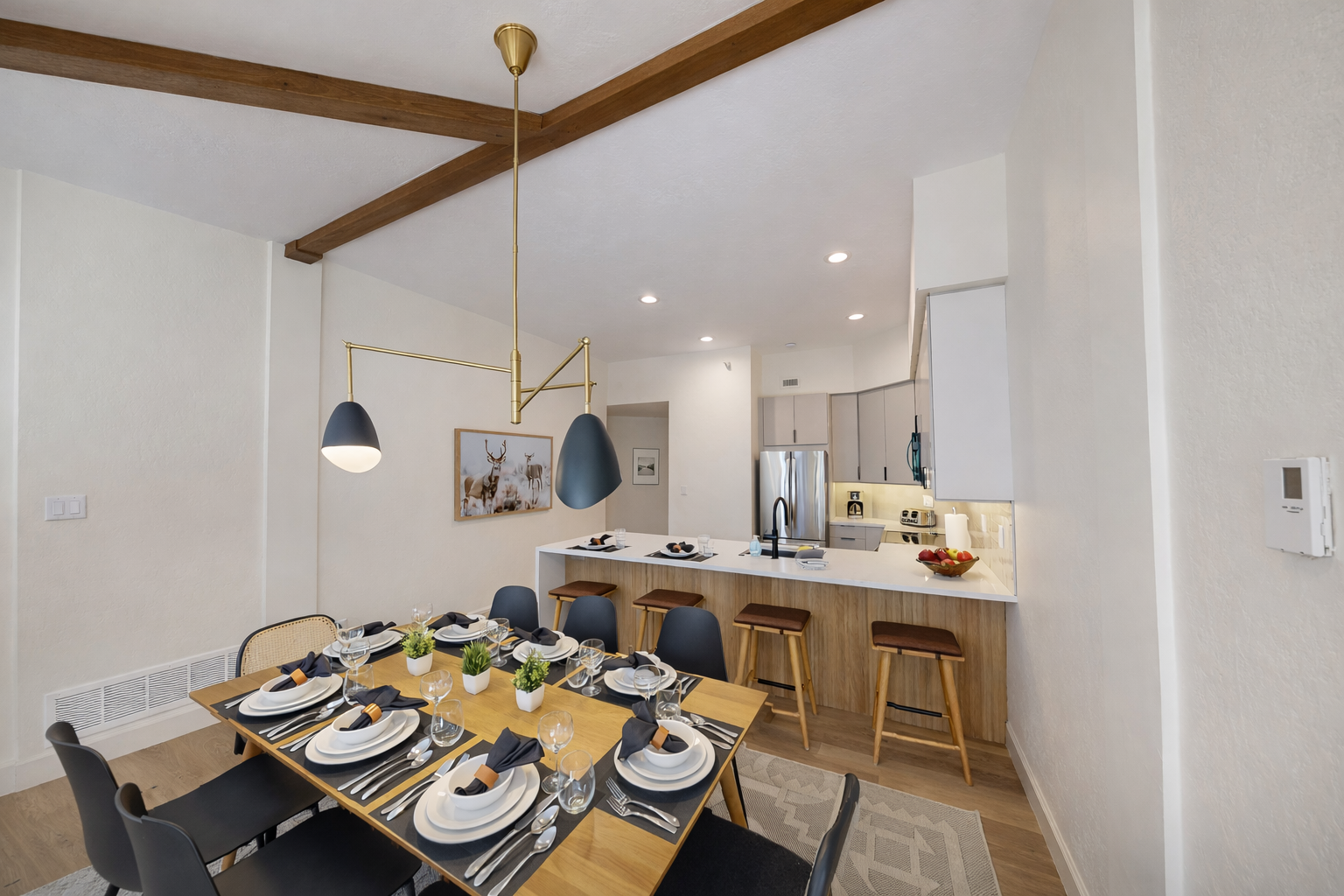 Enjoy meals under a stylish light fixture in this open dining space. It flows into a cozy living room with a stone fireplace, perfect for your mountain getaway.