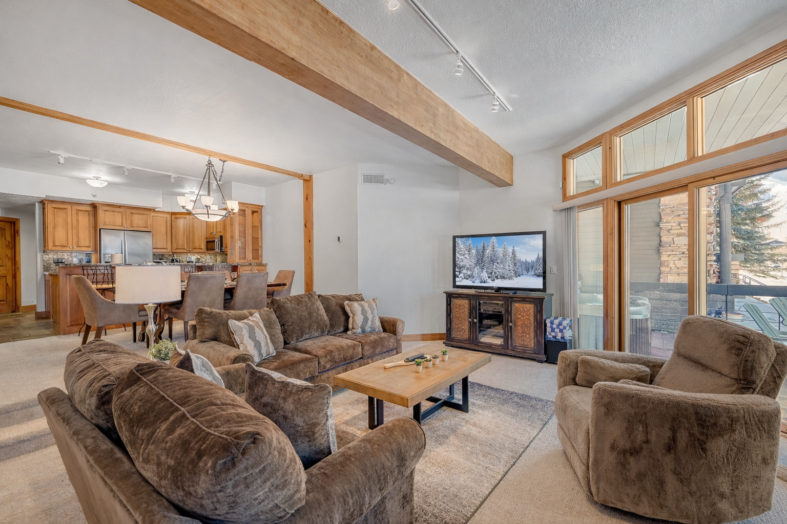 Curl up in your cozy living room with crackling fireplace, plush seating, and stunning winter mountain views through floor-to-ceiling windows.