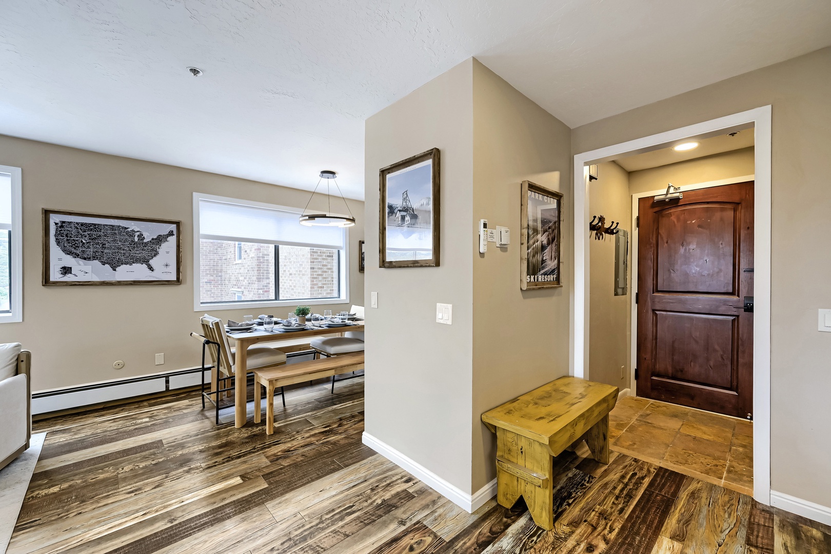 Step into your welcoming entryway where rustic charm meets modern comfort—warm wood floors, a cozy bench for your gear, and an open layout that flows seamlessly into your dining space with mountain views just beyond.