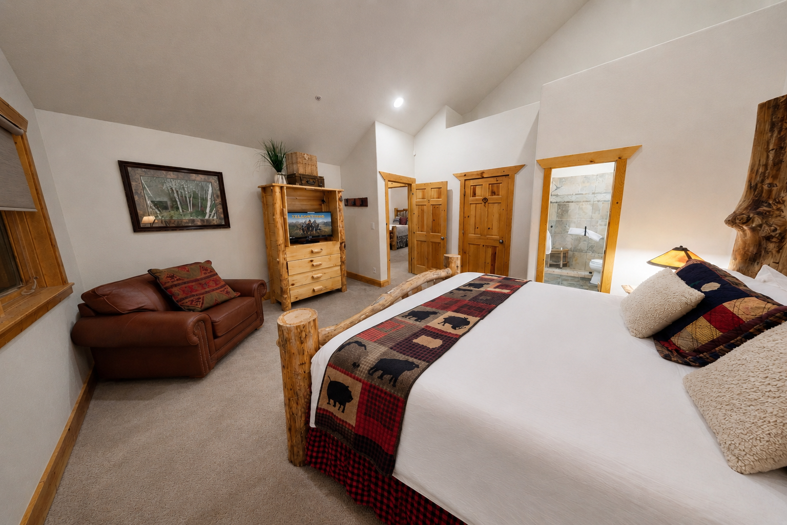 Unwind in your cozy retreat featuring a plush bed with rustic quilted accents, a comfortable leather sofa, and warm wood touches that invite relaxation after your mountain adventures.