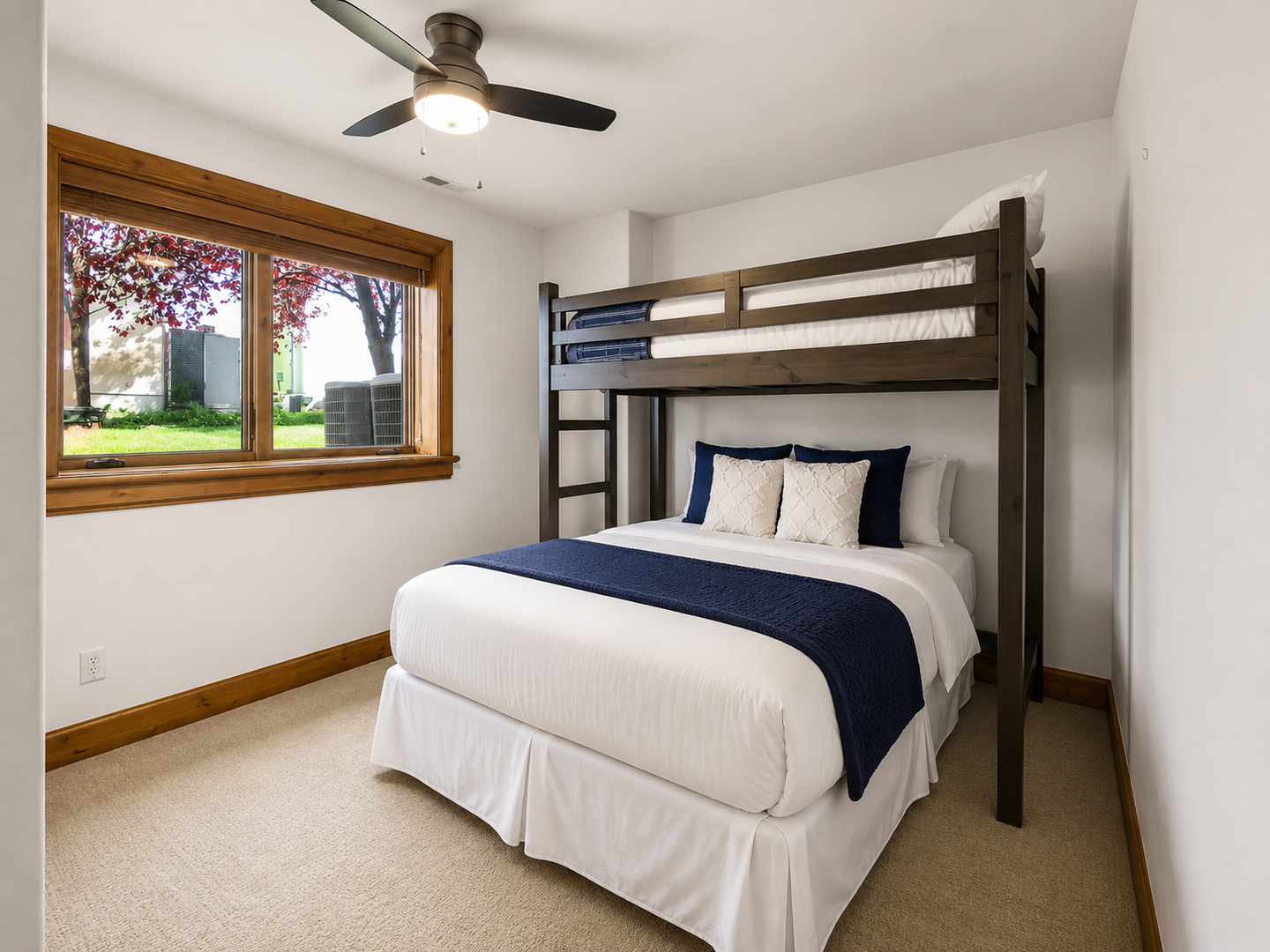 This flexible guest room features a queen bed and overhead twin bunk, perfect for families. Large windows, plush carpeting, and a cooling ceiling fan ensure a bright, comfortable stay.