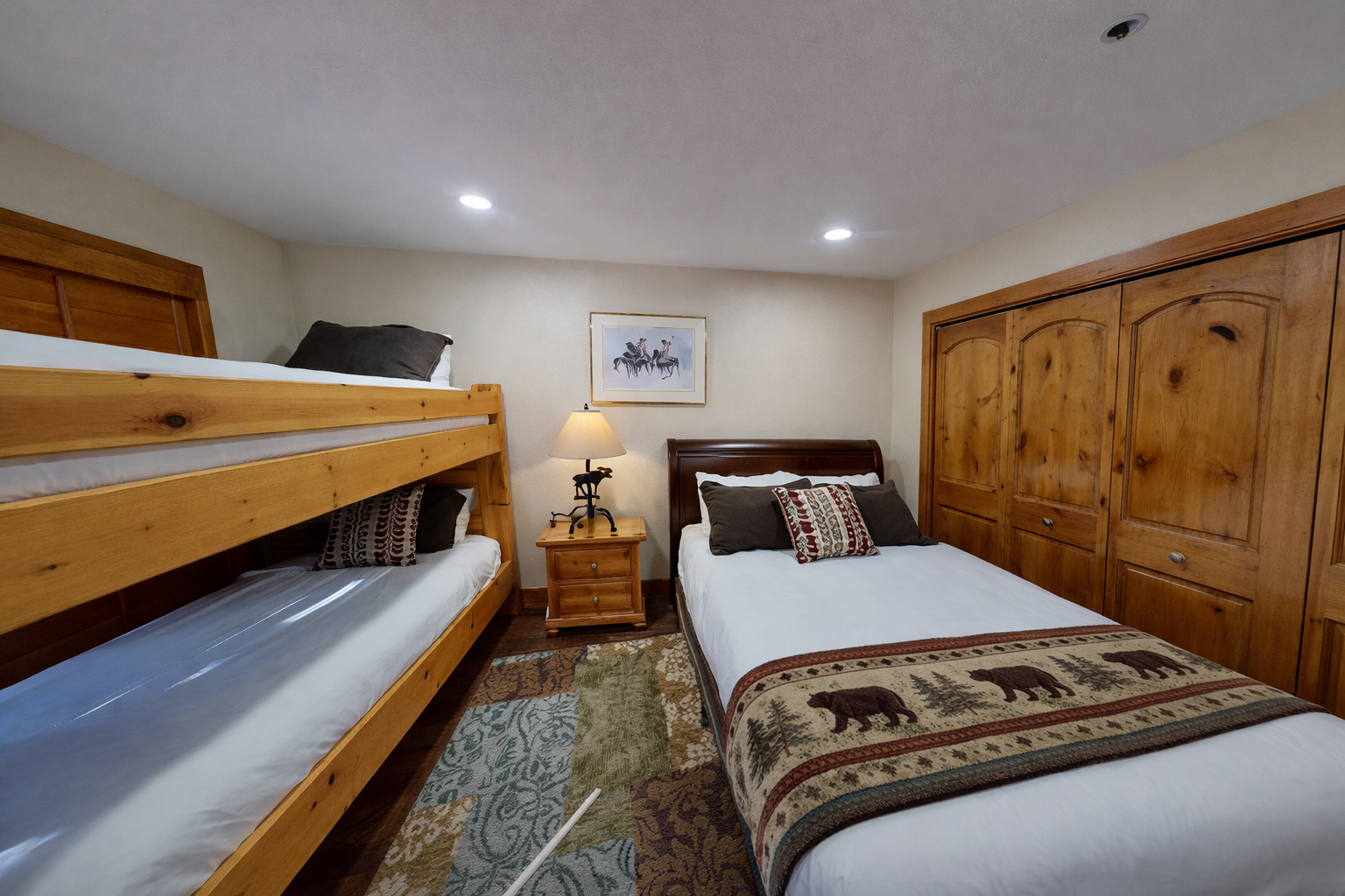 Cozy bedroom with rustic charm features bunk beds and a queen bed, perfect for families seeking mountain lodge comfort.