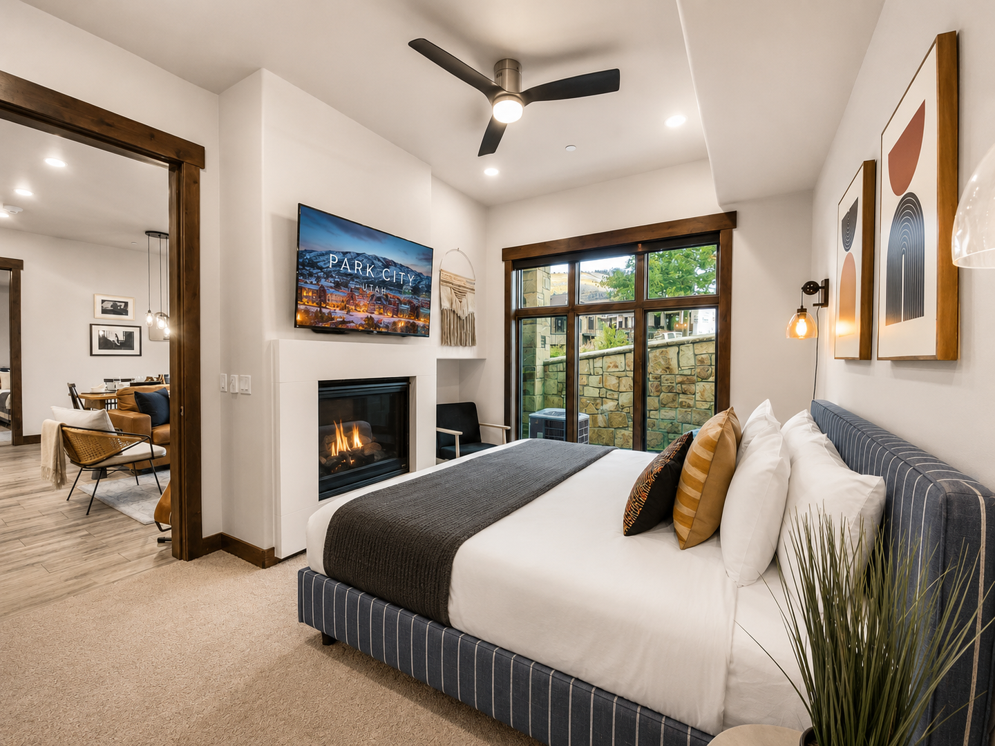 Unwind in your modern bedroom where a cozy fireplace glows beside your plush bed, with large windows framing mountain views and your own private patio access.