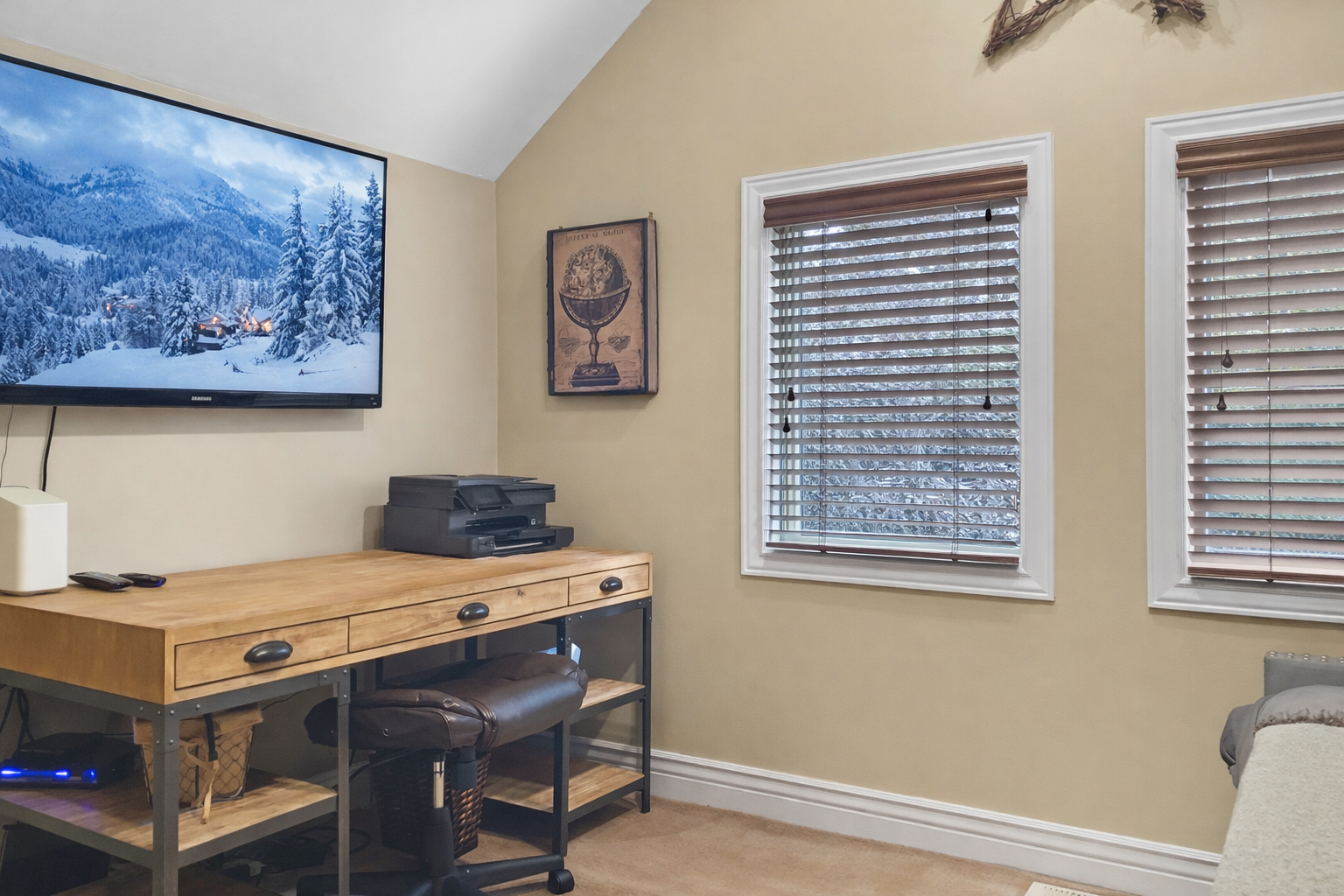 Your dedicated workspace features a natural wood desk, ergonomic chair, and wall-mounted TV for both productivity and relaxation.