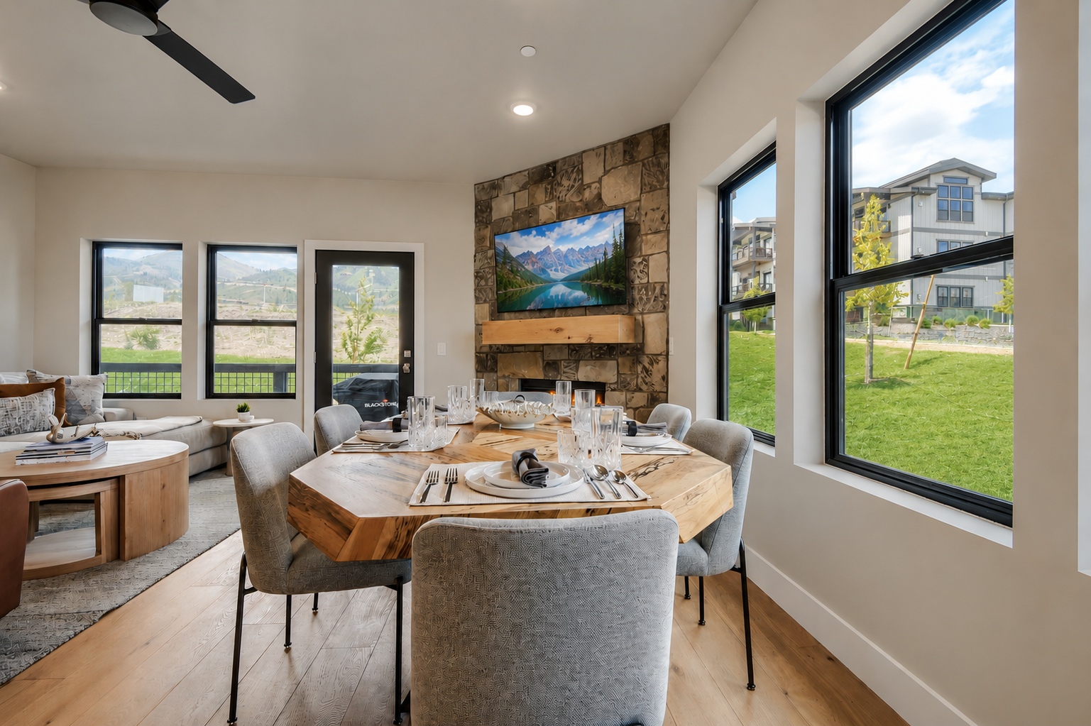 Gather around this stunning live-edge dining table set for eight, where your group can share memorable meals beside a rustic stone fireplace. Picture yourself enjoying morning coffee as natural light streams through expansive windows.