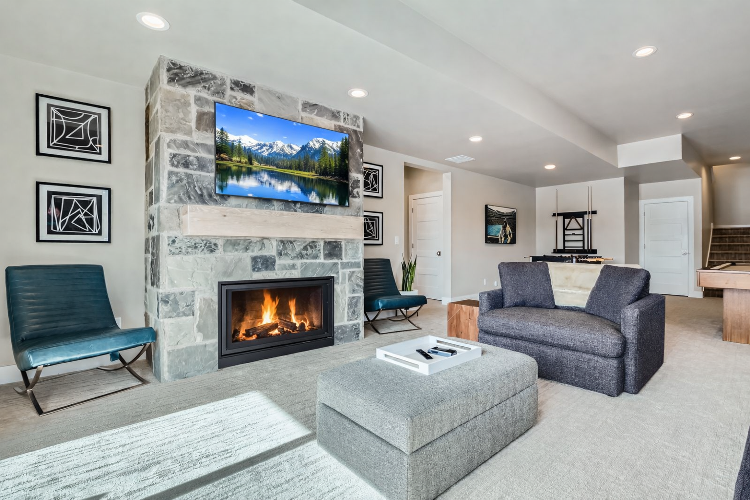 Unwind in this cozy living area featuring a stunning stone fireplace and large TV. With plush seating and a warm, inviting atmosphere, it's the perfect spot for movie nights.