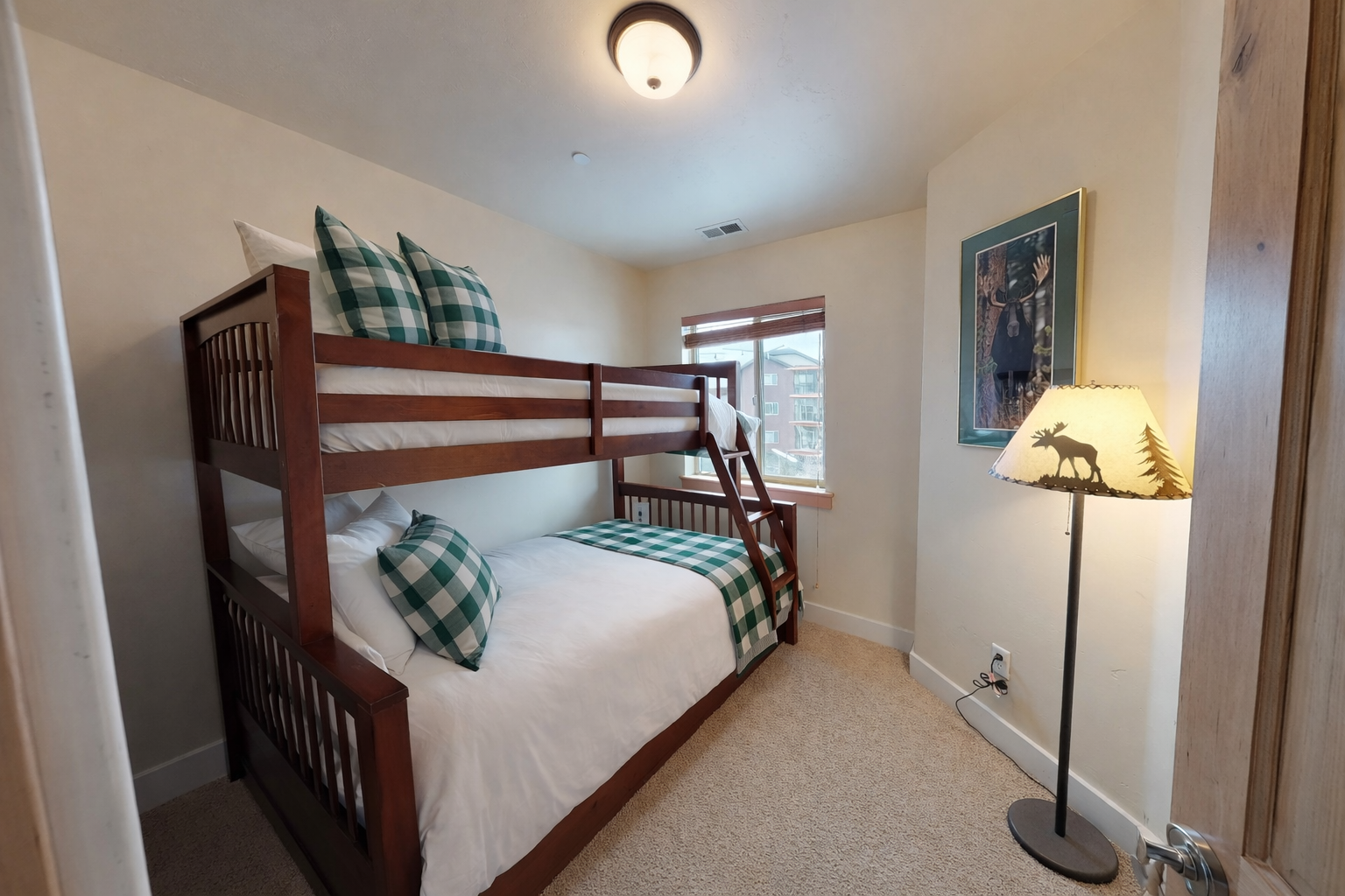 Your cozy bunk room features charming green gingham bedding and warm wood frames, perfect for family adventures together.