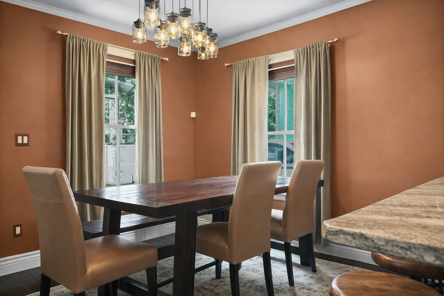 Gather around this inviting dining table beneath a stunning chandelier. Natural light floods through large windows, creating the perfect setting for your memorable meals together.