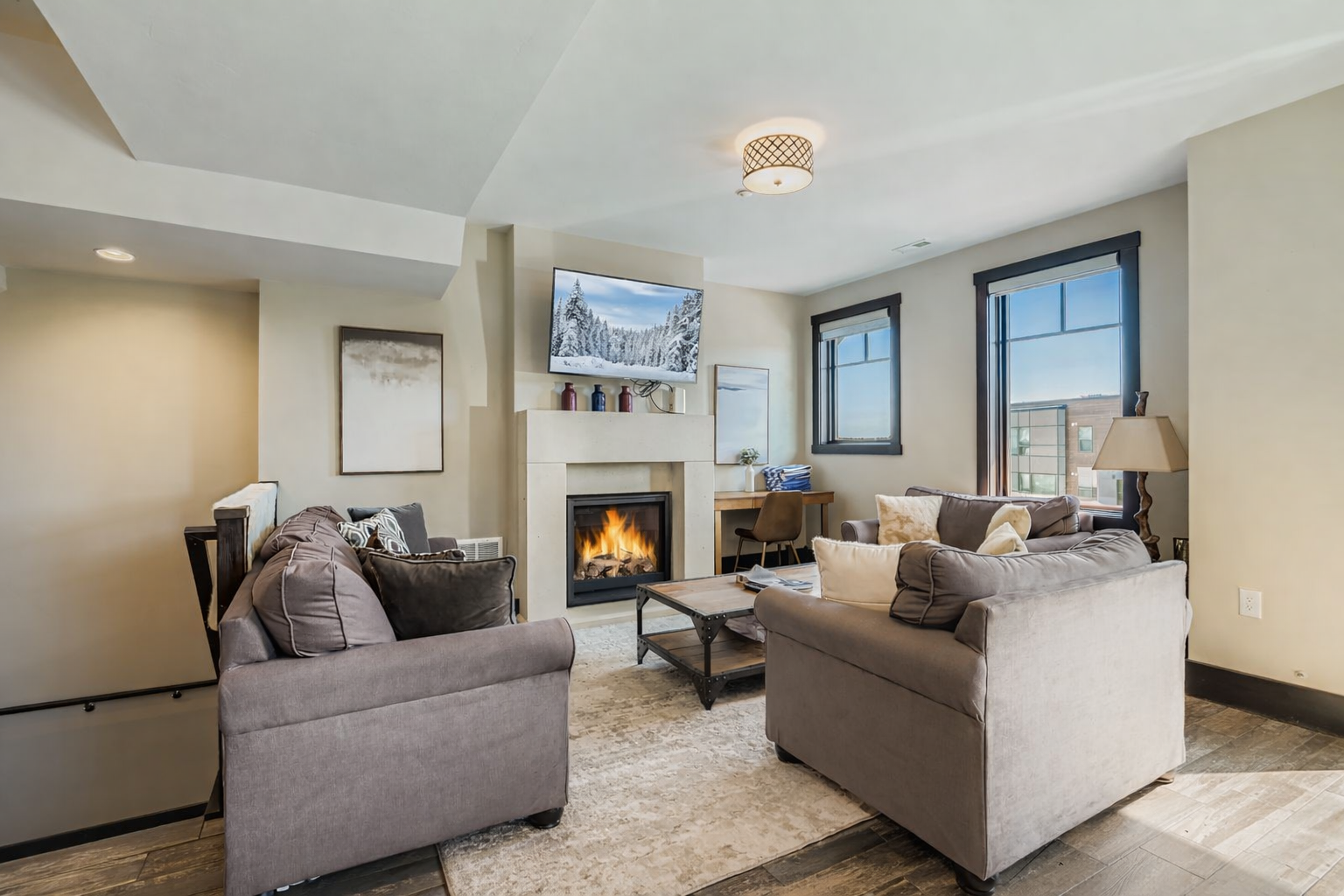 Relax in this light-filled open living area featuring a cozy gas fireplace, plush seating, and a large smart TV.