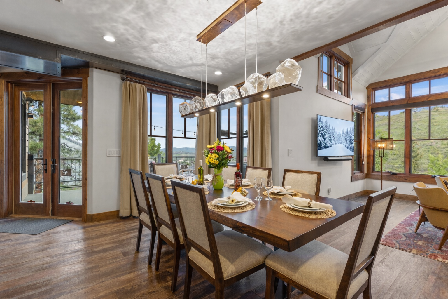 Dine in style in this open-concept area featuring a large wood dining table, modern pendant lighting, and easy access to the kitchen.