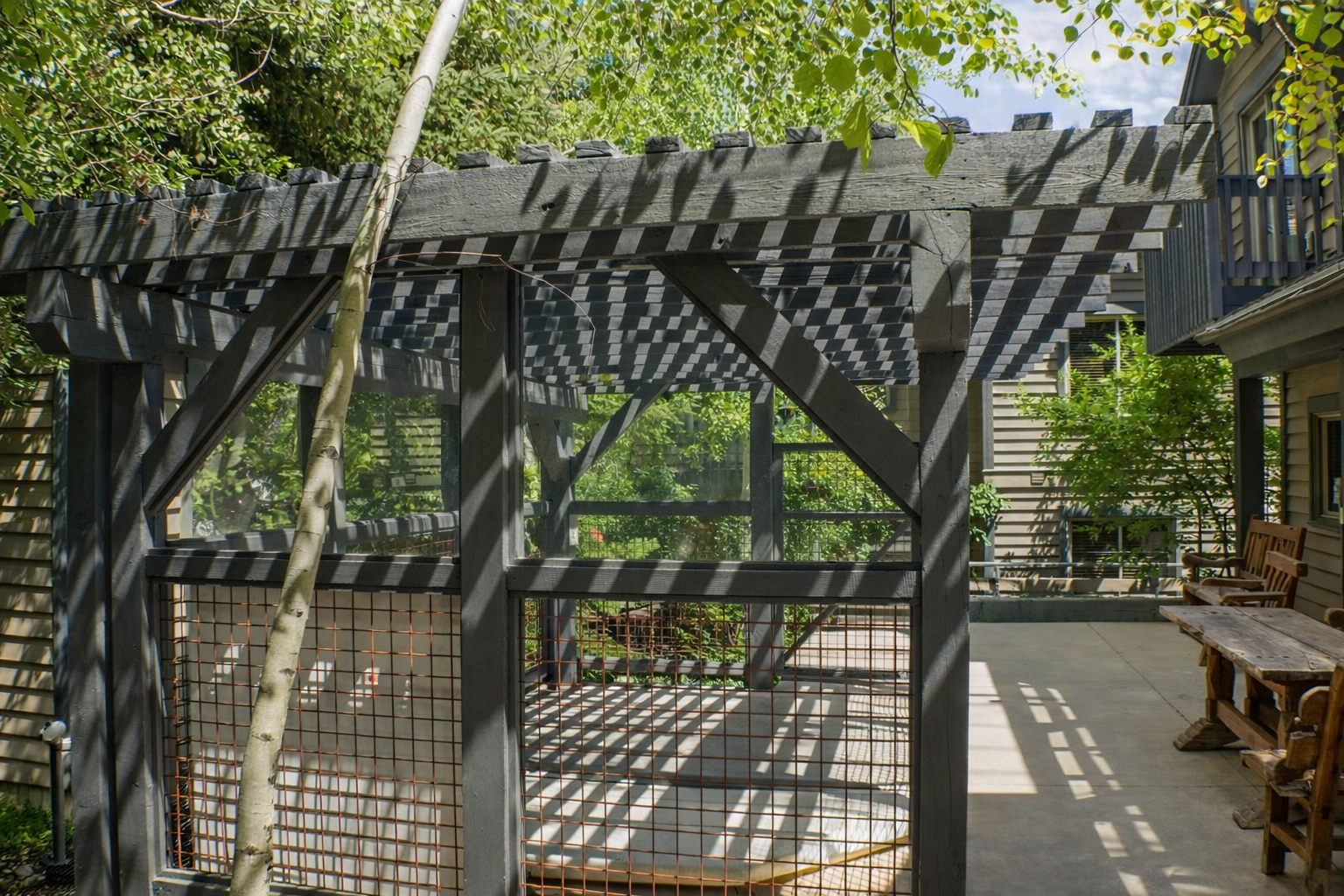 Your community outdoor terrace features a relaxing hot tub, BBQ grill, and comfortable seating surrounded by peaceful trees.