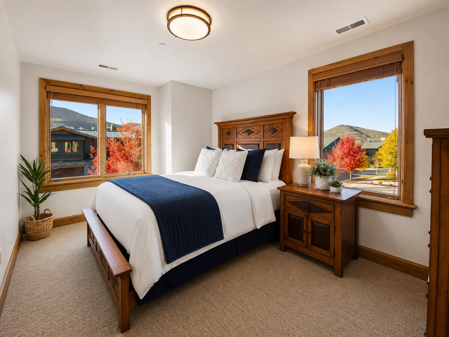 This sun-drenched guest room features a sturdy wood-framed queen bed, plush linens, and dual oversized windows. Enjoy stunning views of the surrounding mountain landscape from the comfort of your room.