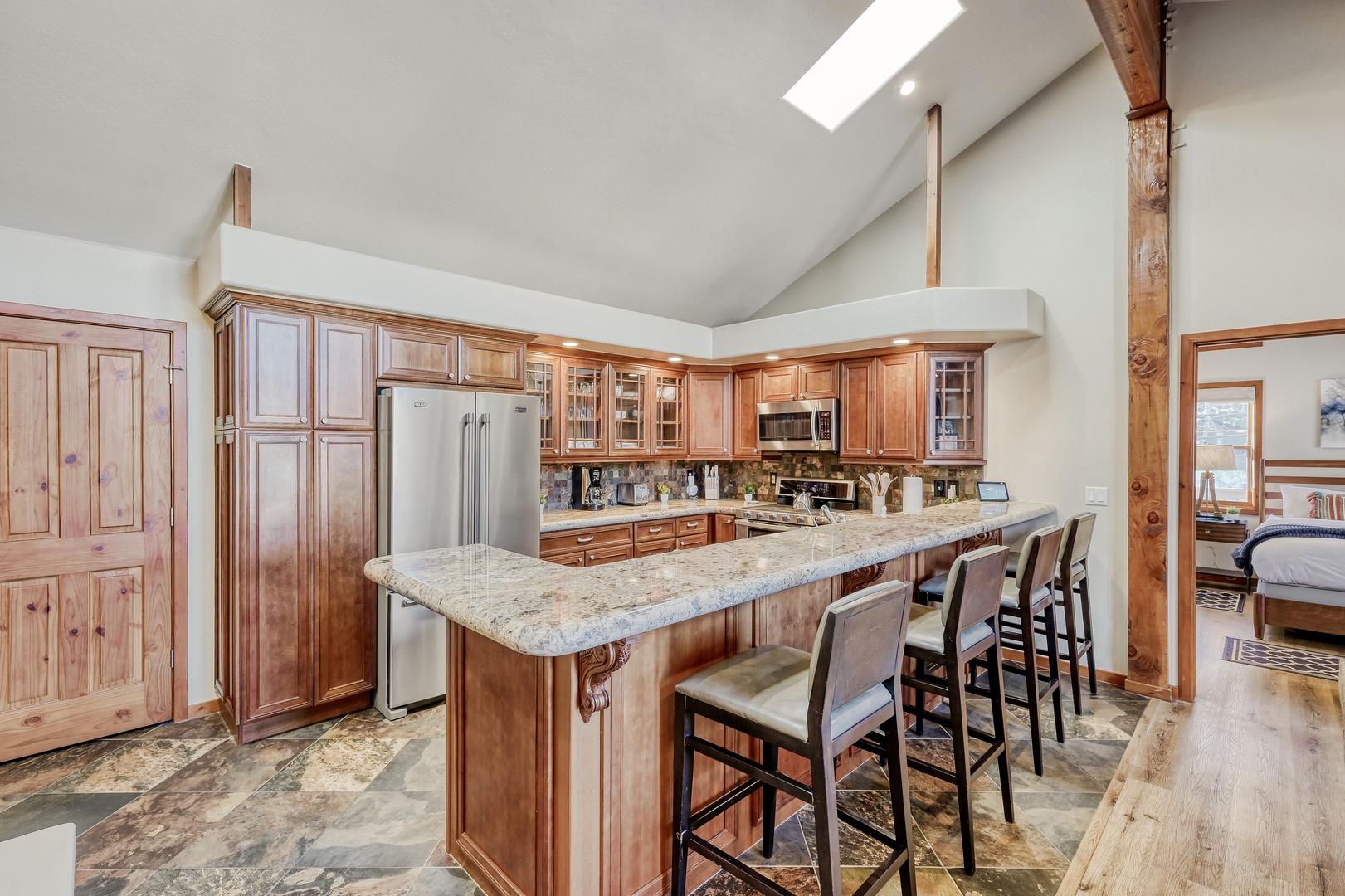 Gather around the expansive granite island in this bright, fully-equipped kitchen where natural light pours through the skylight above. With bar seating for everyone, it's your perfect spot for morning coffee or evening conversations.