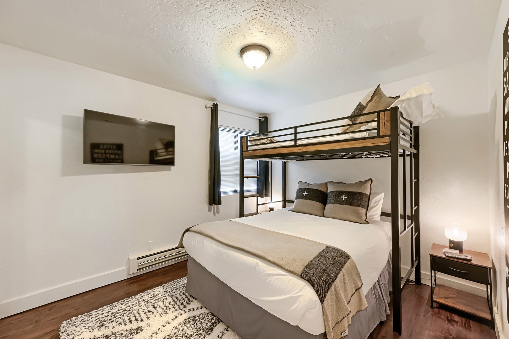 Your cozy bedroom features a unique bunk bed setup—perfect for families or friends traveling together. Clean white walls, warm wood floors, and soft bedding create a restful retreat after a day of adventure.