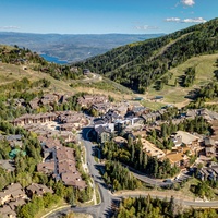 A stunning aerial view captures the property nestled in a lush mountain valley, surrounded by rolling hills and expansive natural beauty.