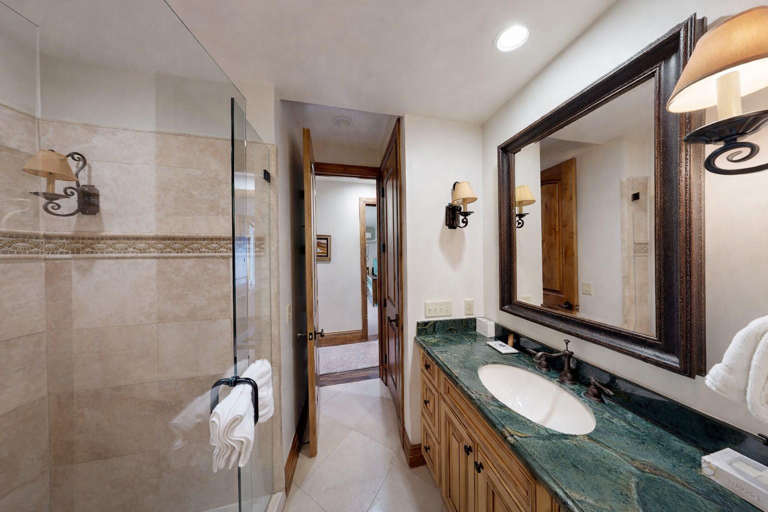 Your spacious bathroom features elegant stone counters, a glass shower, and warm lighting for ultimate relaxation.