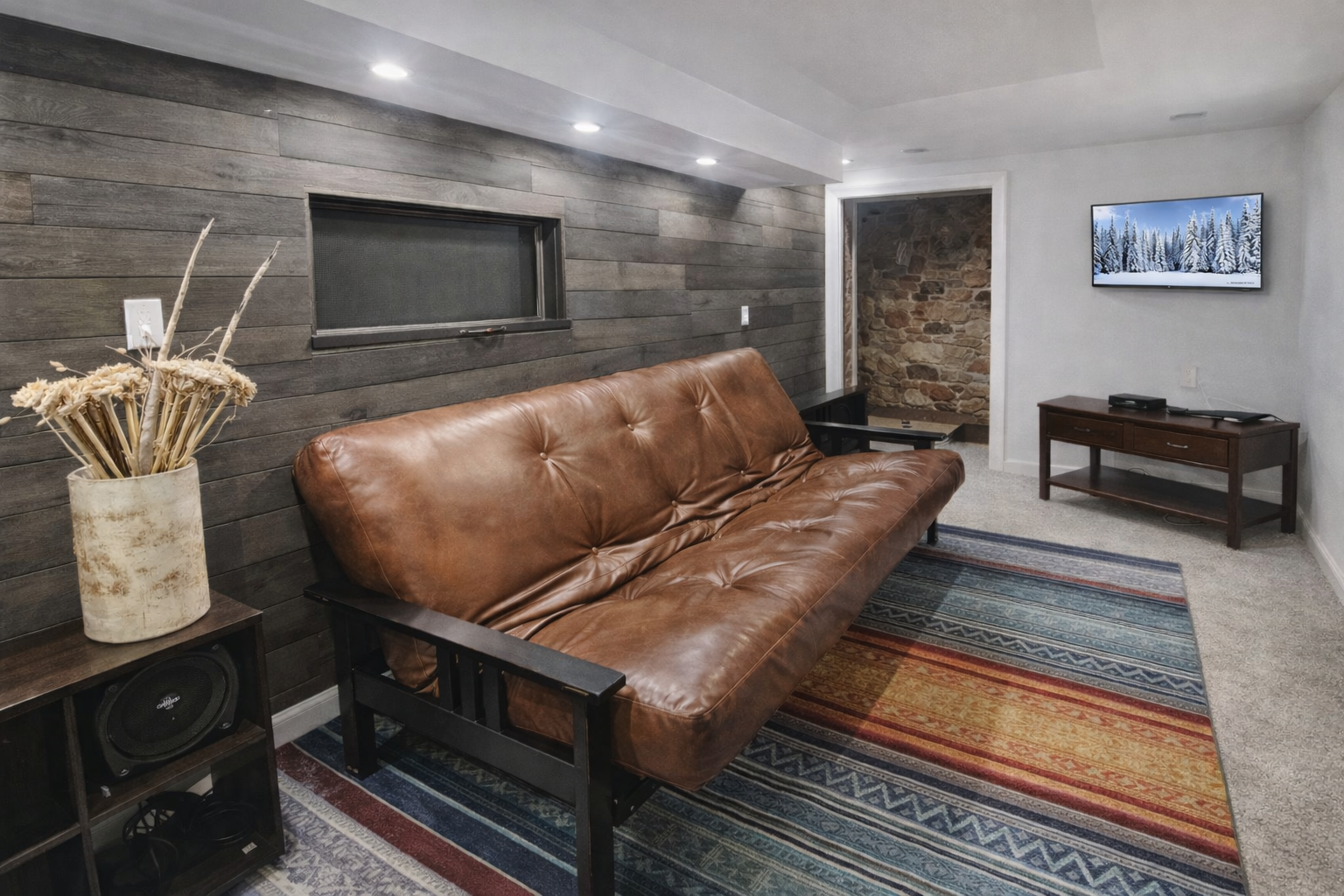 Cozy space featuring a comfortable leather futon and rustic wood/stone accents. A charming, multi-use room for your mountain getaway.