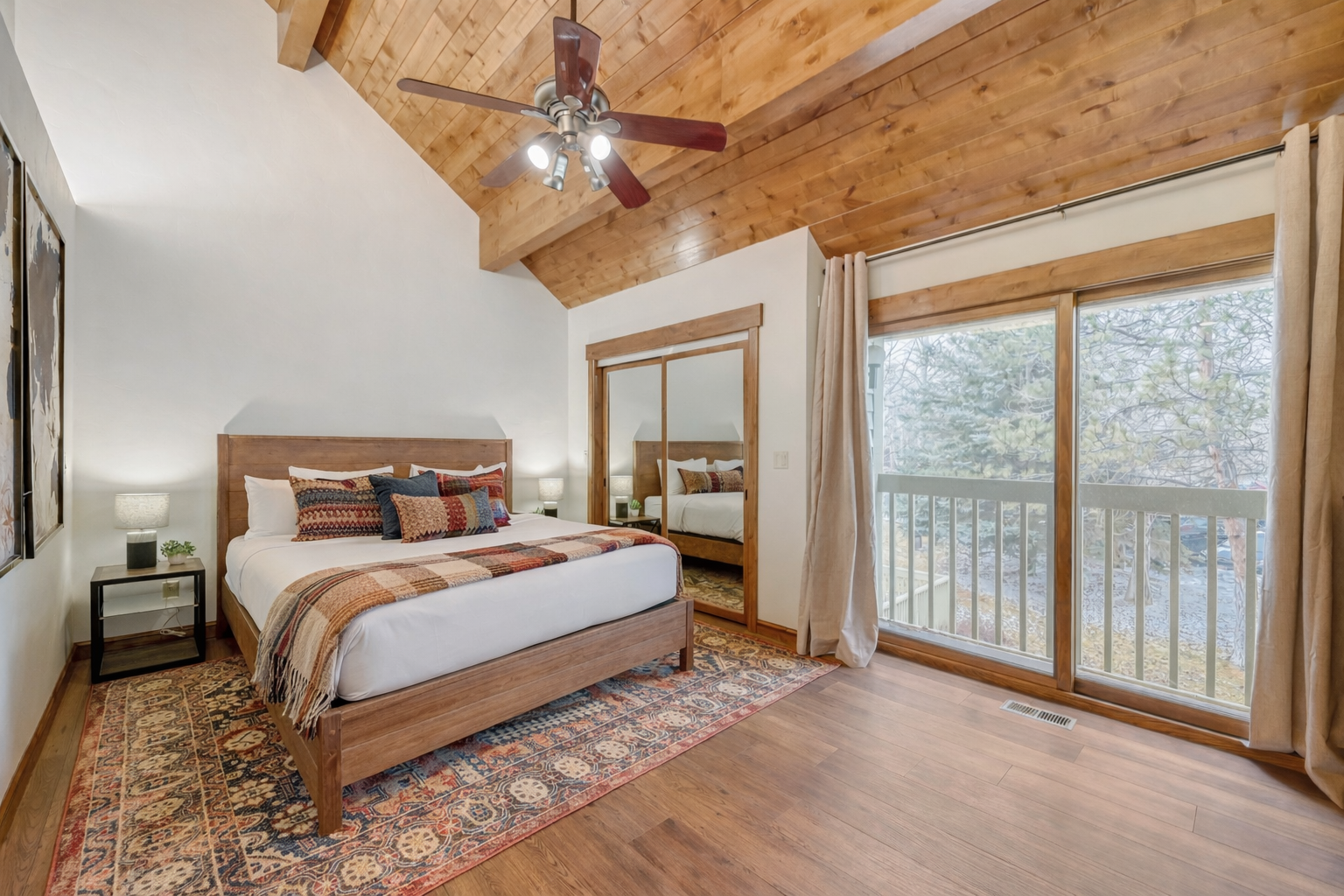 Drift off beneath rustic wood beams and wake to forest views from your private balcony in this cozy bedroom.
