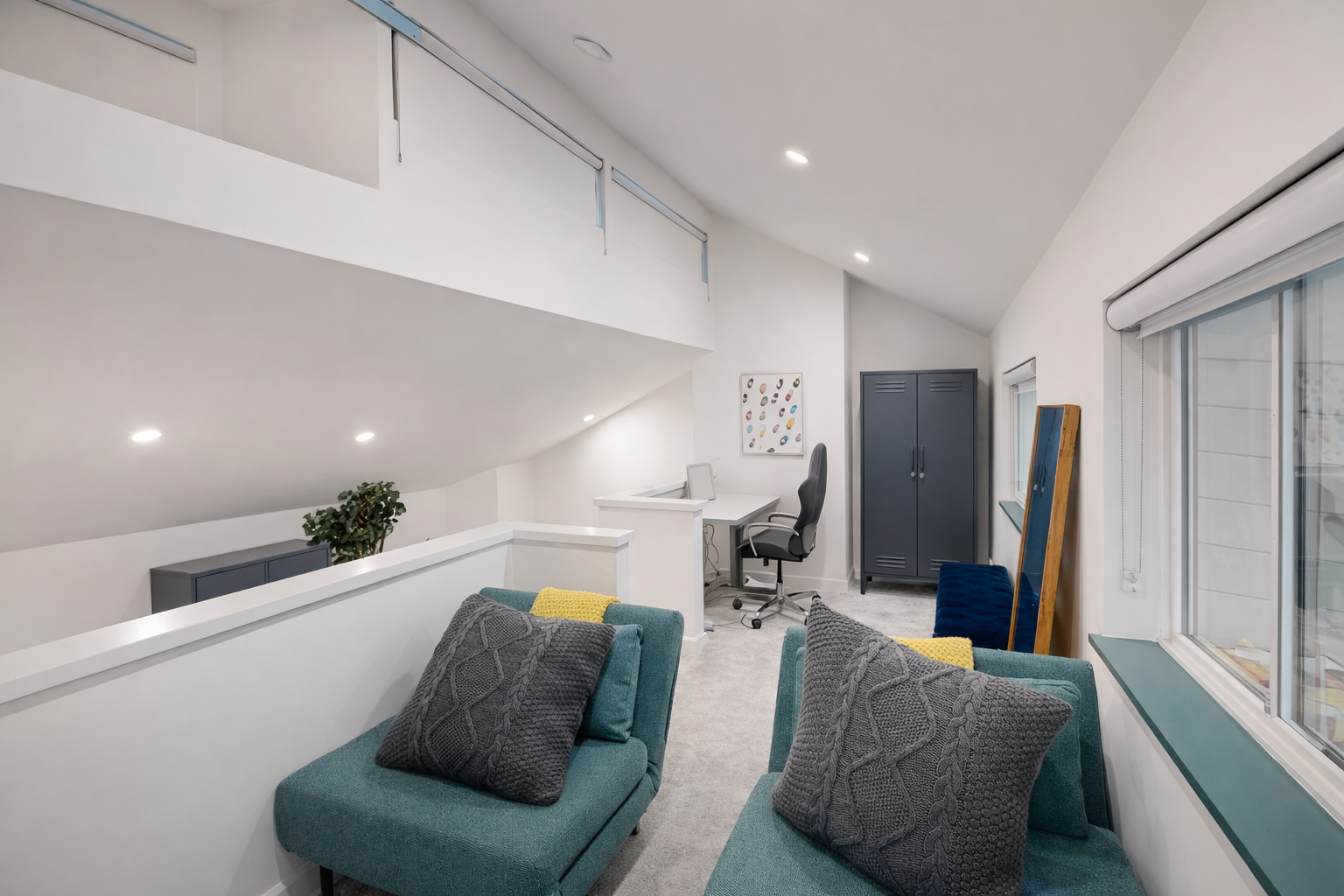 Unwind in your stylish loft space with plush teal seating, cozy pillows, and a dedicated workspace perfect for relaxing or catching up.