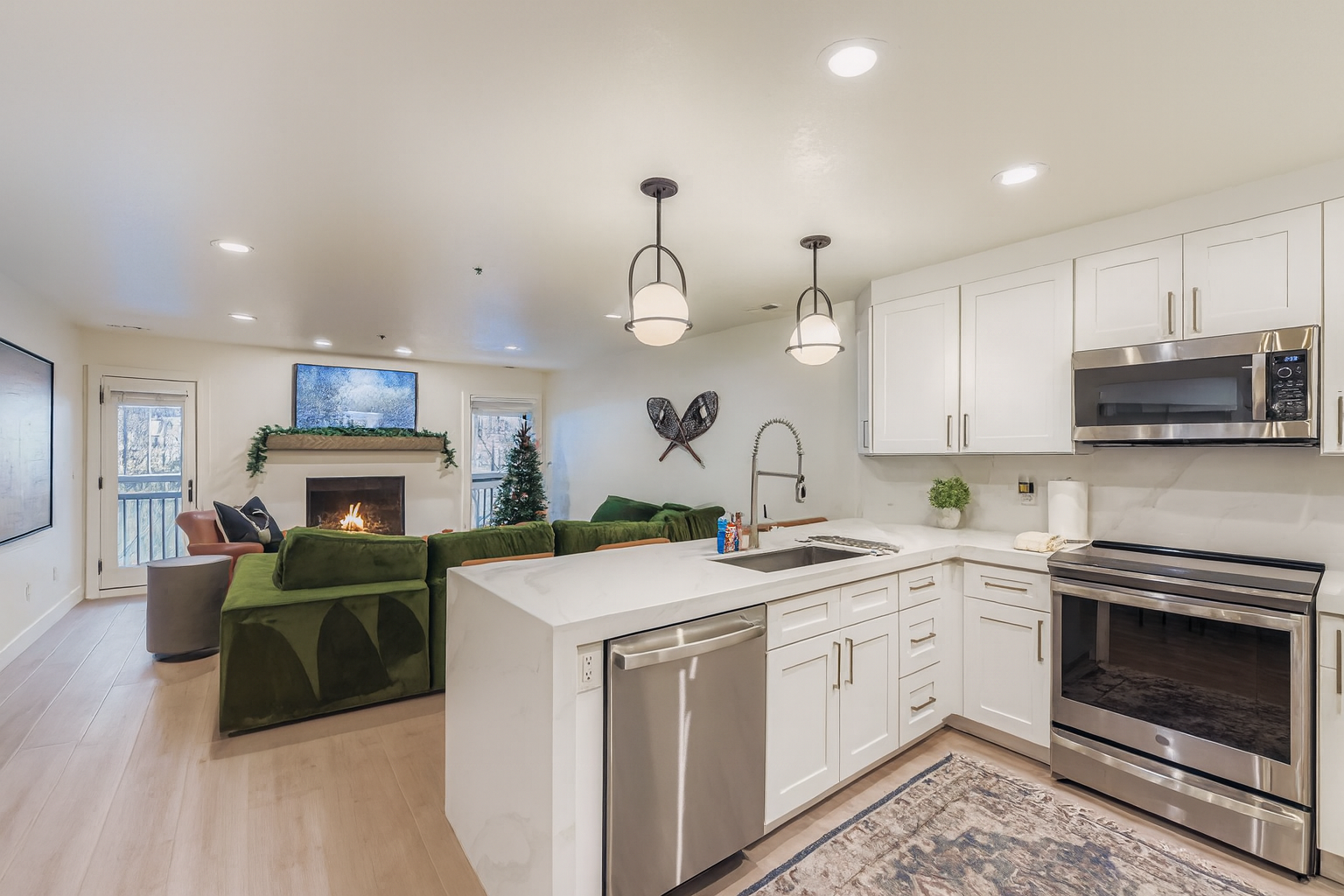 Your modern open-concept living space features a fully equipped kitchen with stainless steel appliances, cozy fireplace seating area, and bright, welcoming atmosphere.