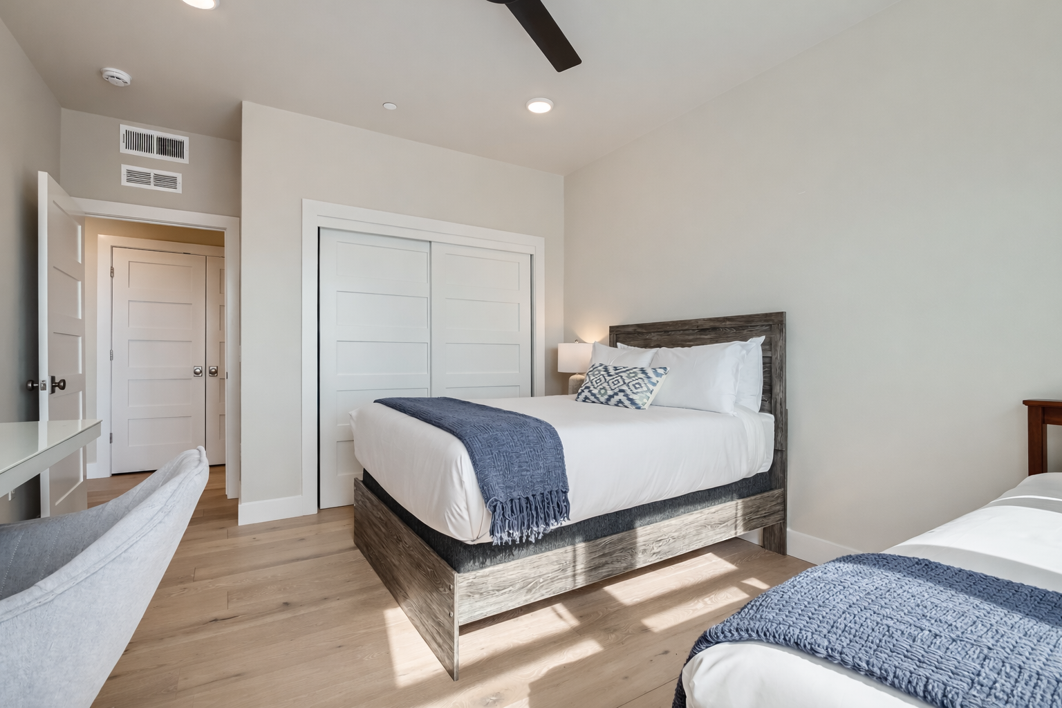 Relax in this bright, modern bedroom featuring two cozy beds with rustic wood frames. Sun-drenched and airy, it’s the perfect spot to rest and recharge after a day of exploring.