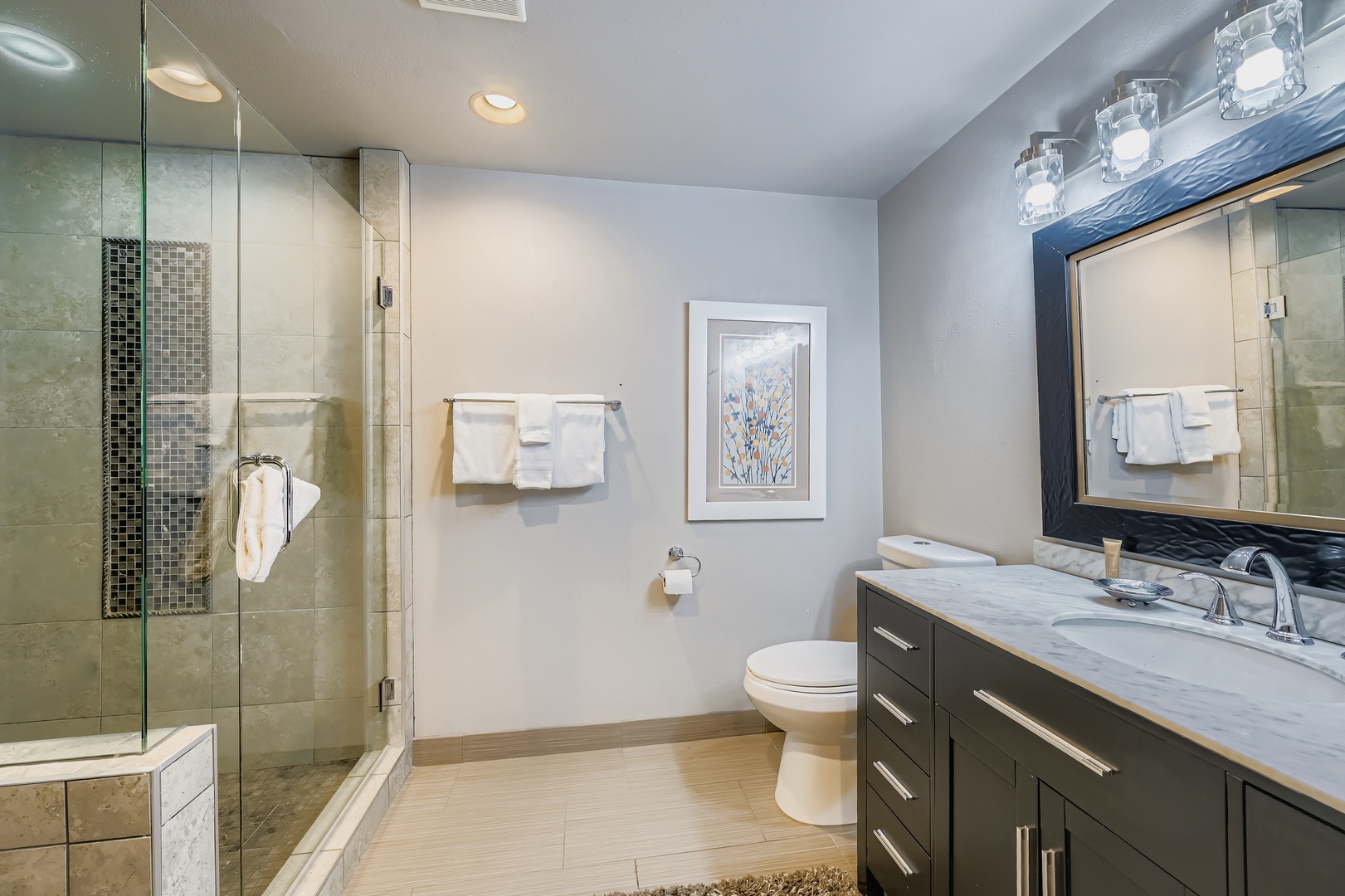 Step into this spa-inspired bathroom where soft lighting meets modern elegance. With a spacious glass shower, generous countertops, and plush towels awaiting your arrival, every detail invites you to unwind.