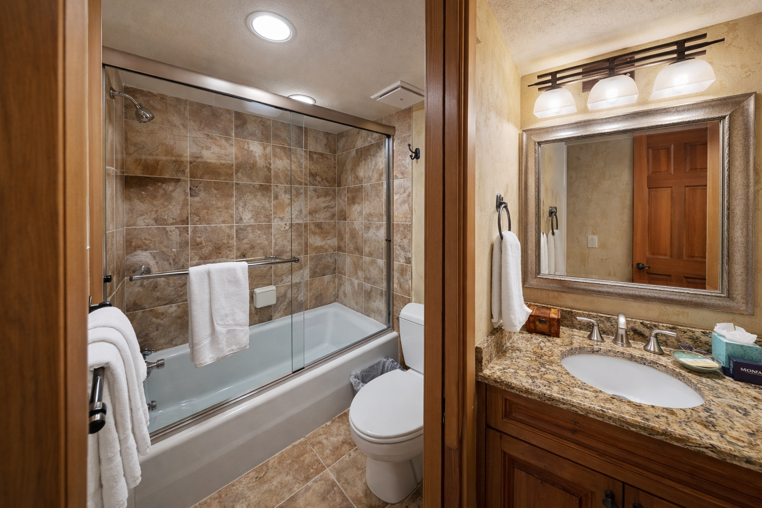Unwind in your elegant bathroom featuring granite counters, rich wood cabinetry, and a soothing tub-shower combo for relaxing after your adventures.