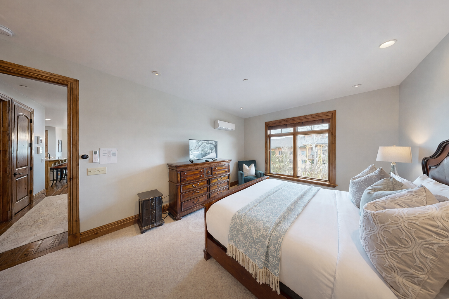 This spacious master suite features a luxurious king bed, soft linens, and a large dresser with a smart TV. Recessed lighting and neutral tones create a bright, tranquil retreat.