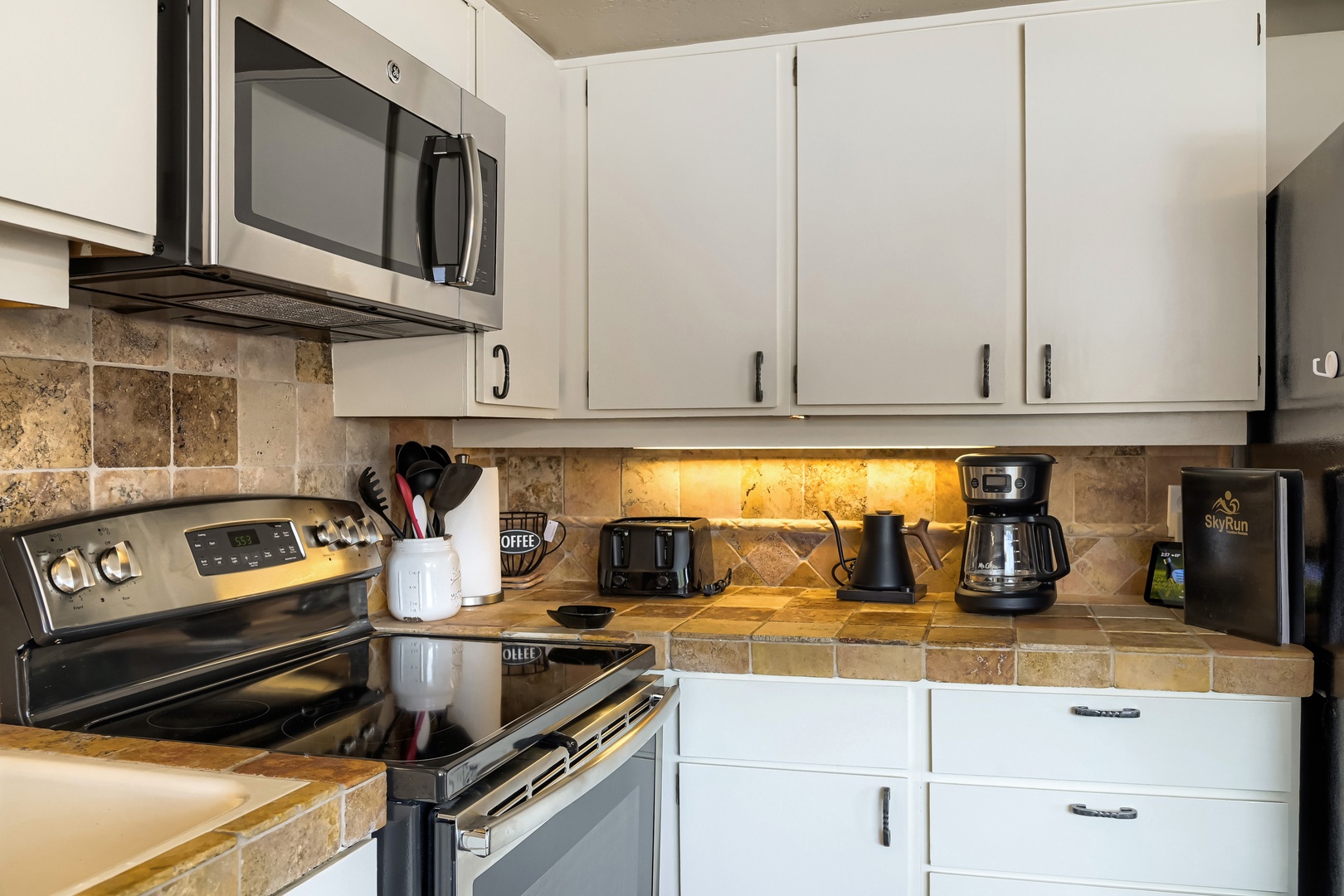 Your fully equipped kitchen features modern stainless steel appliances, warm under-cabinet lighting, and a charming tile backsplash, with everything you need to whip up meals at your own pace.