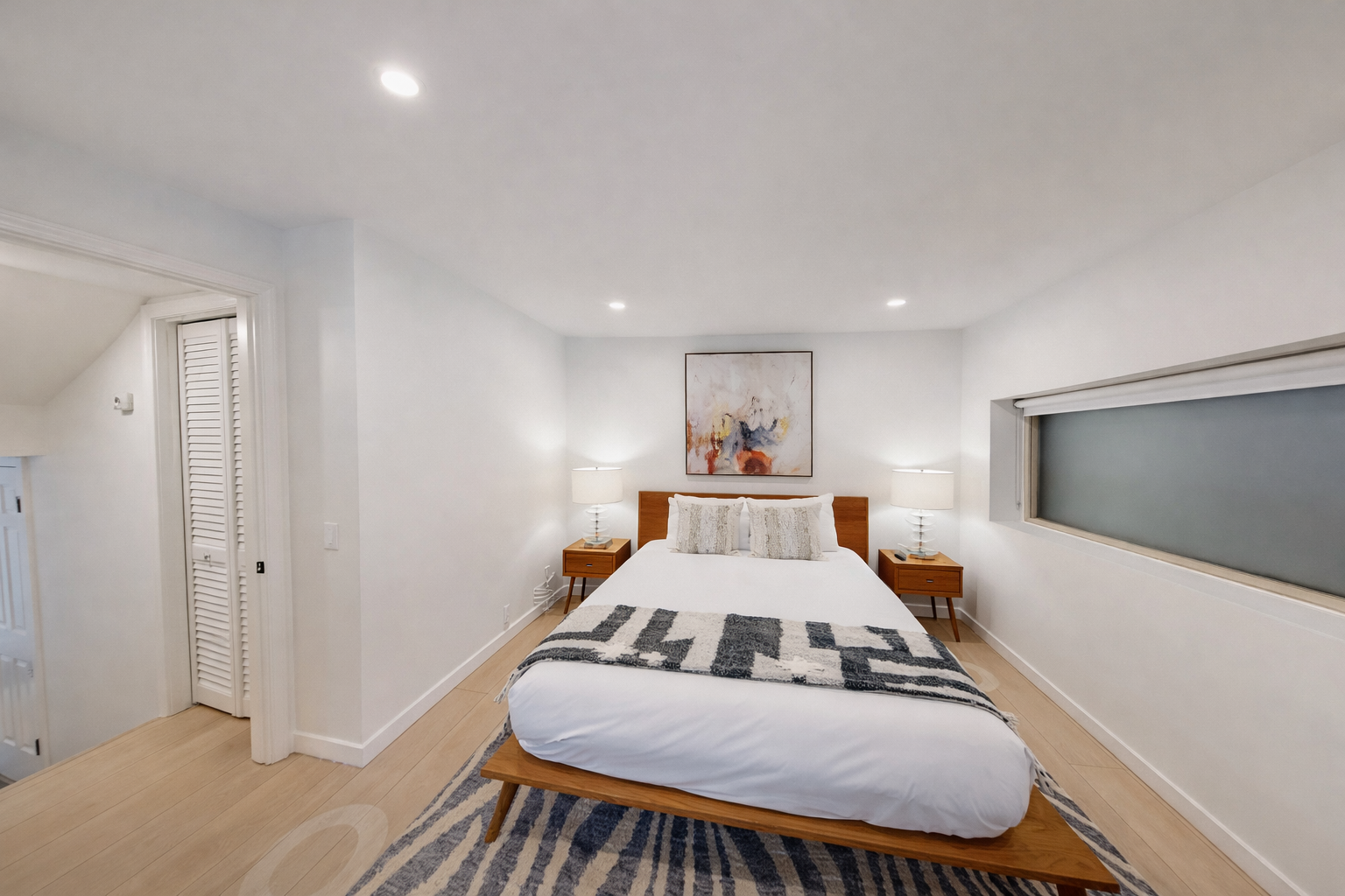Relax in this serene, modern bedroom with a comfortable bed, ample storage, and a dedicated spin bike.