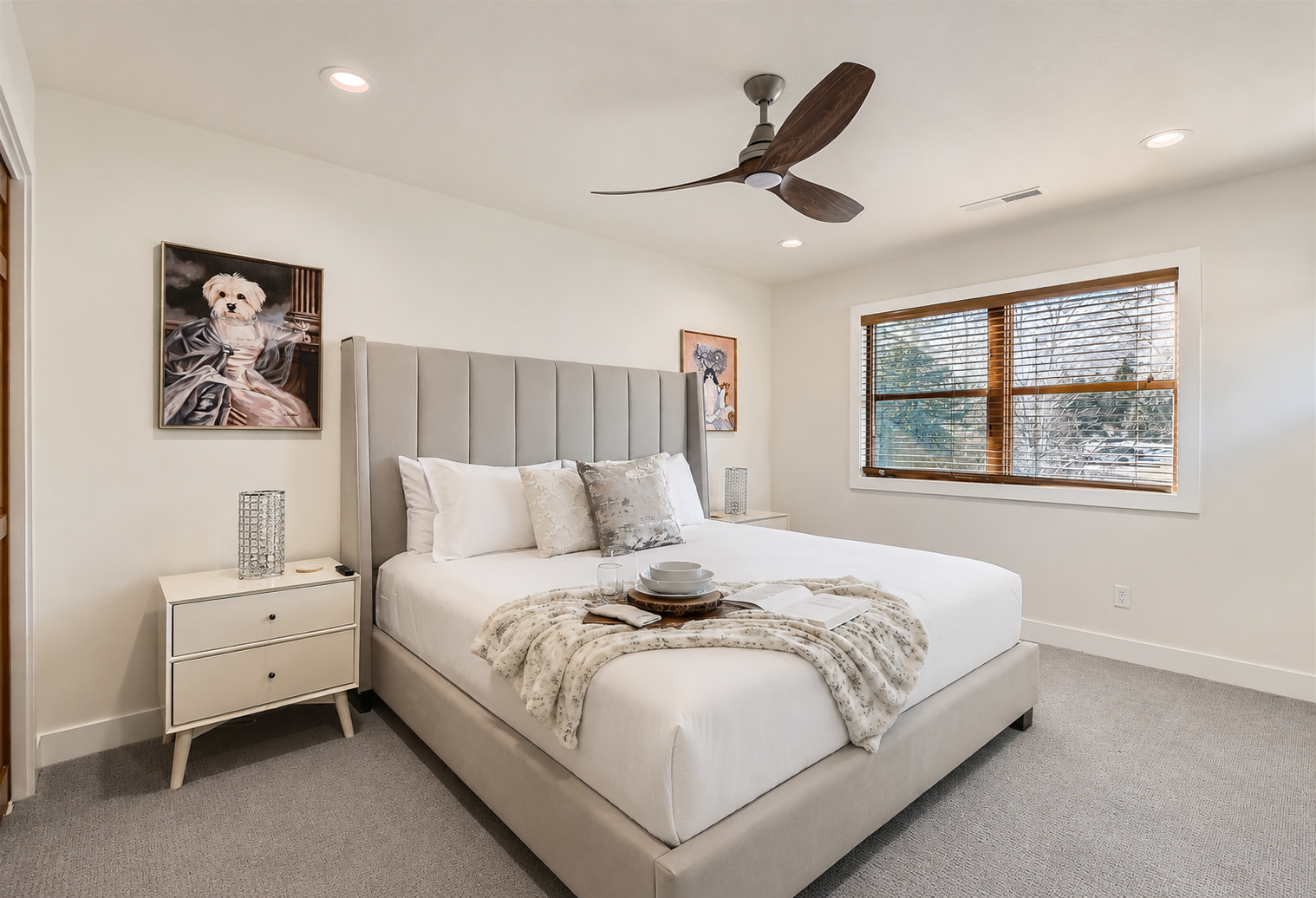 Retire to this quiet, modern bedroom with an upholstered king bed, soft lighting, and ceiling fan, the perfect escape after a busy day.